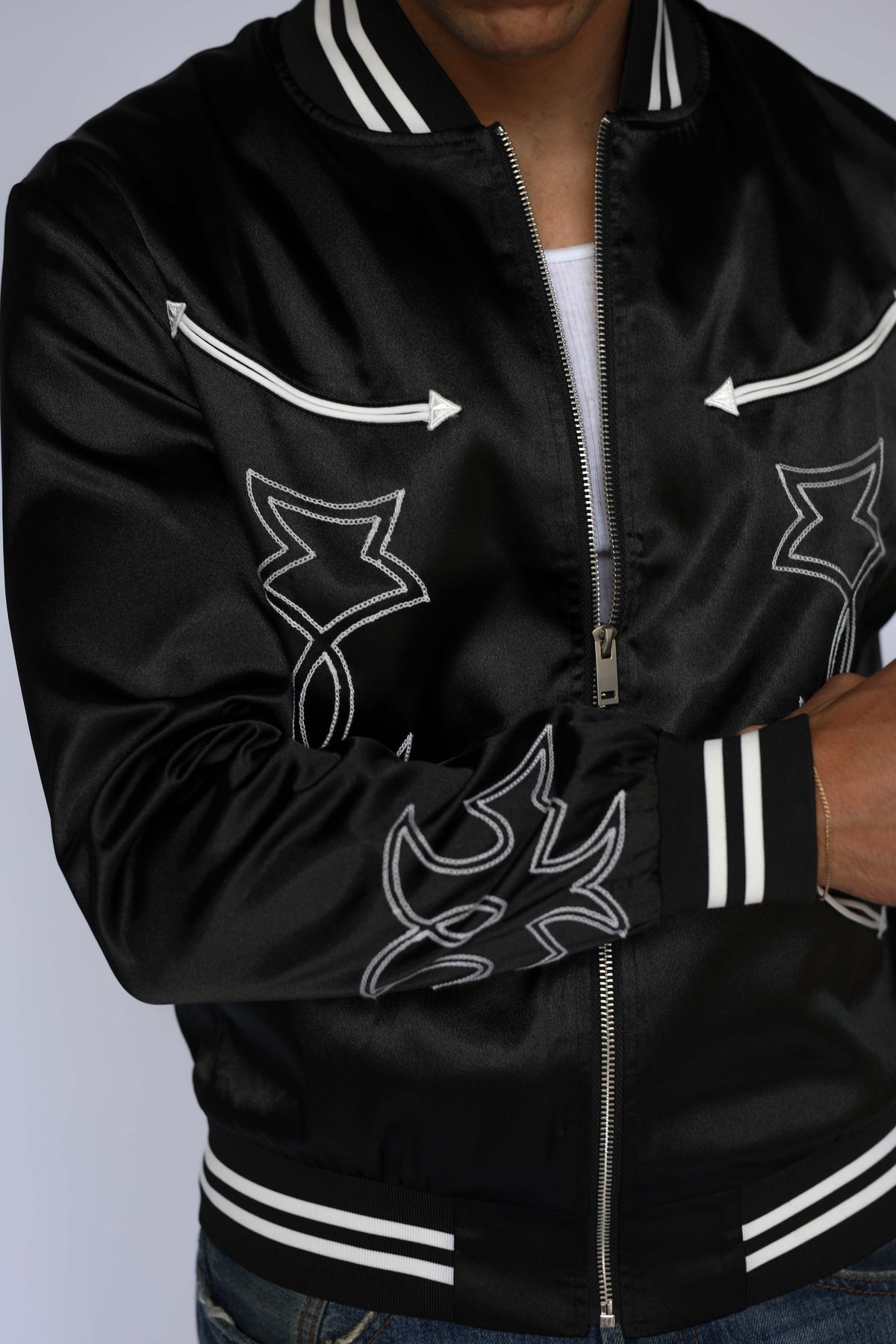 Detail of the H Bar C Odessa black satin jacket front with white arrow appliqués and chain stitch embroidery, vintage inspired western wear.