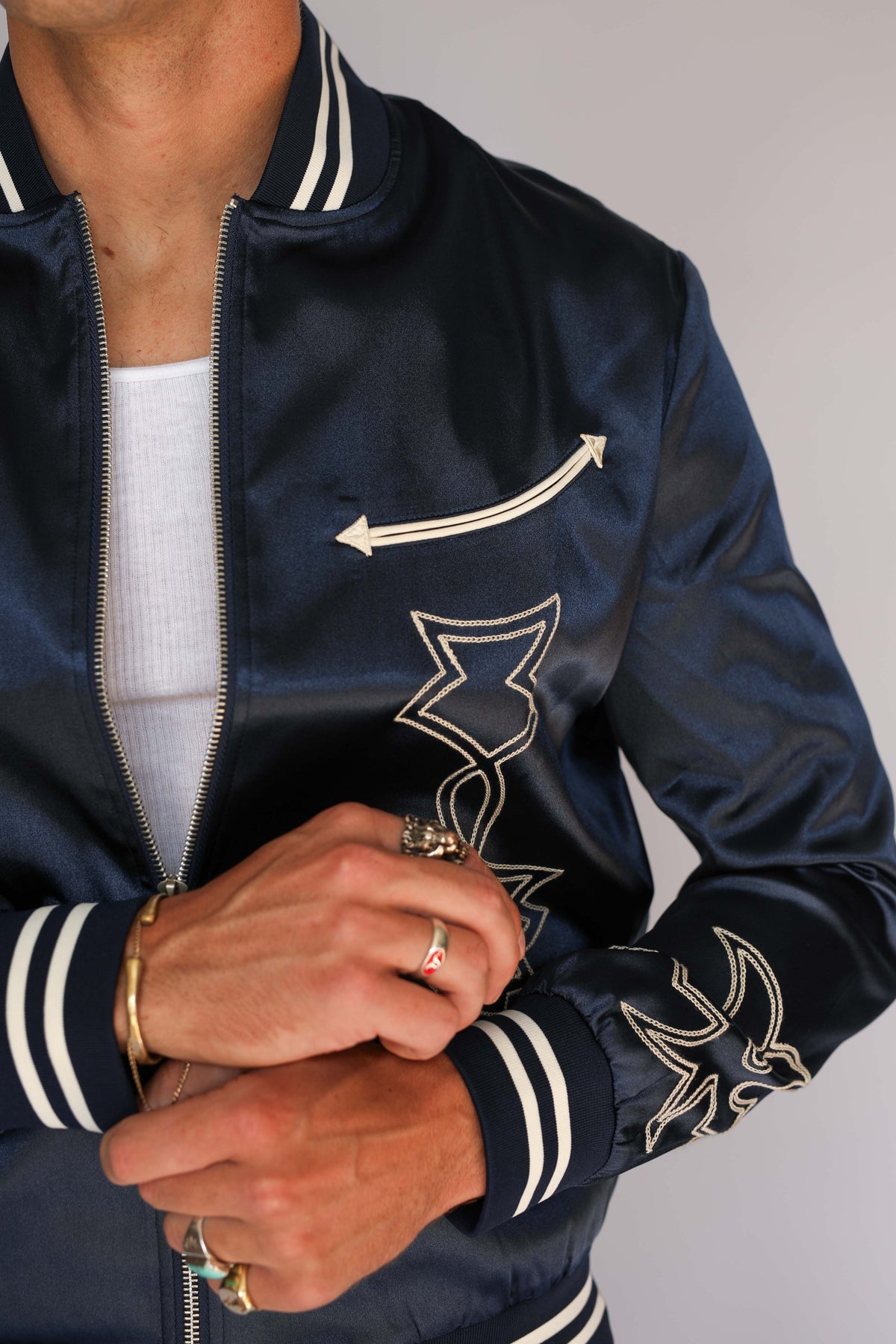 Detail of the H Bar C Odessa navy tour jacket zipper, embroidered sleeve, and navy and cream striped cuff, vintage inspired western wear.