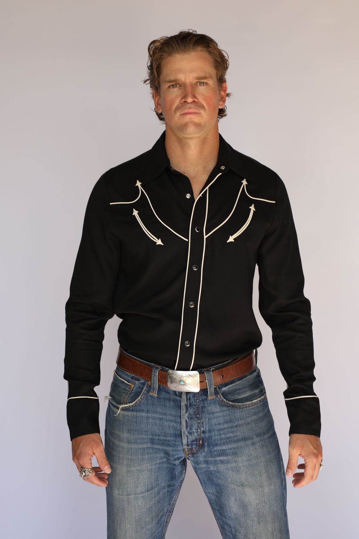 Man wearing the H Bar C Reno black western shirt with off-white piping and arrow embroidery, vintage inspired western wear in a Man in Black tribute.