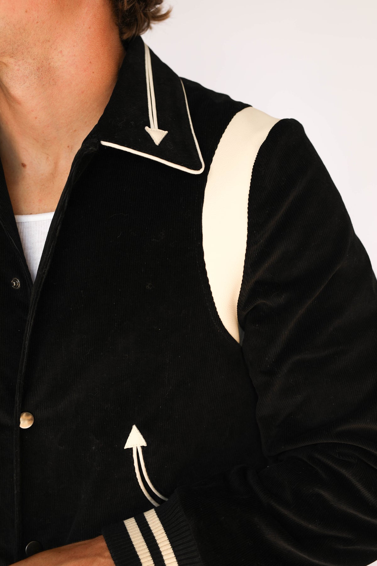 Close-up of the H Bar C Silver Lake black corduroy jacket showing the cream piped collar with arrow tip, lambskin shoulder panel, and arrow pocket, vintage western wear detail.