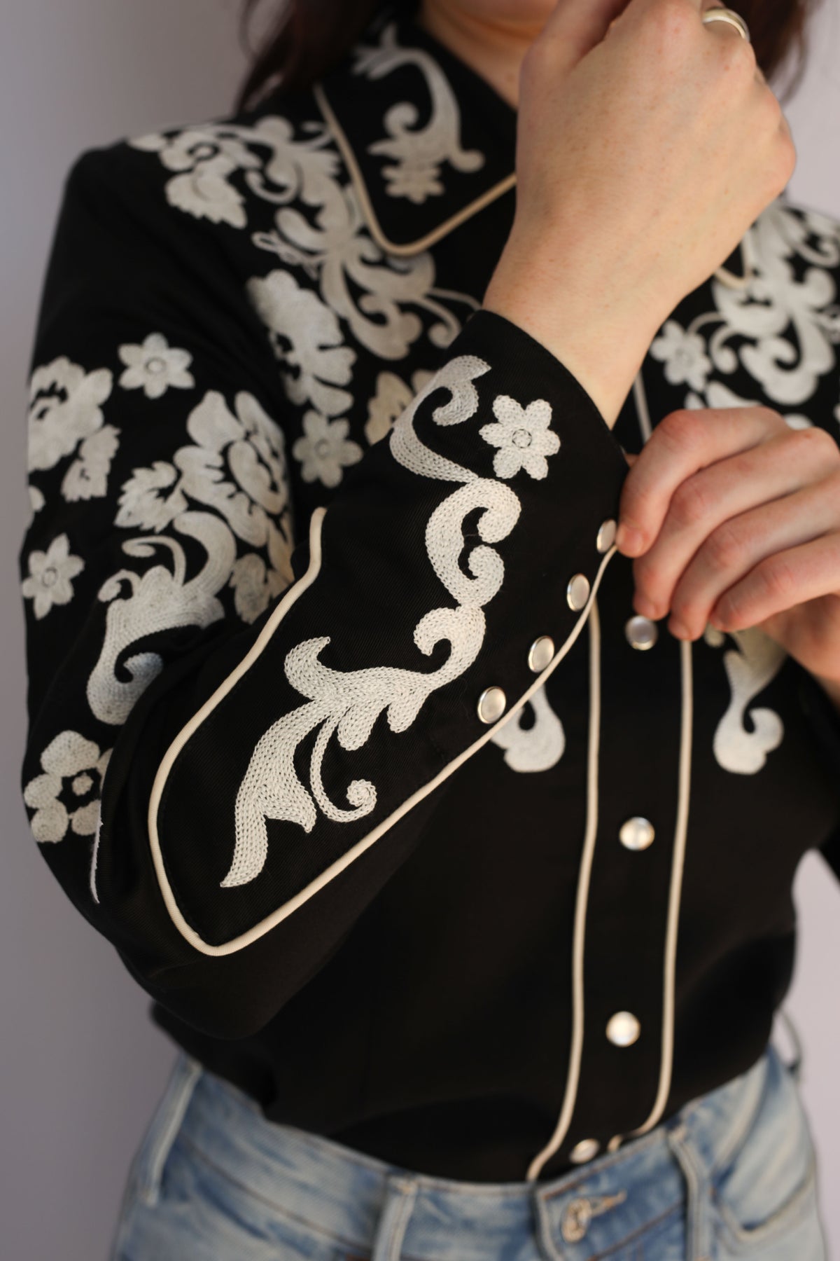 Detail of the ivory chain stitch floral embroidery on the H Bar C Fort Worth women's black western shirt, vintage western wear.