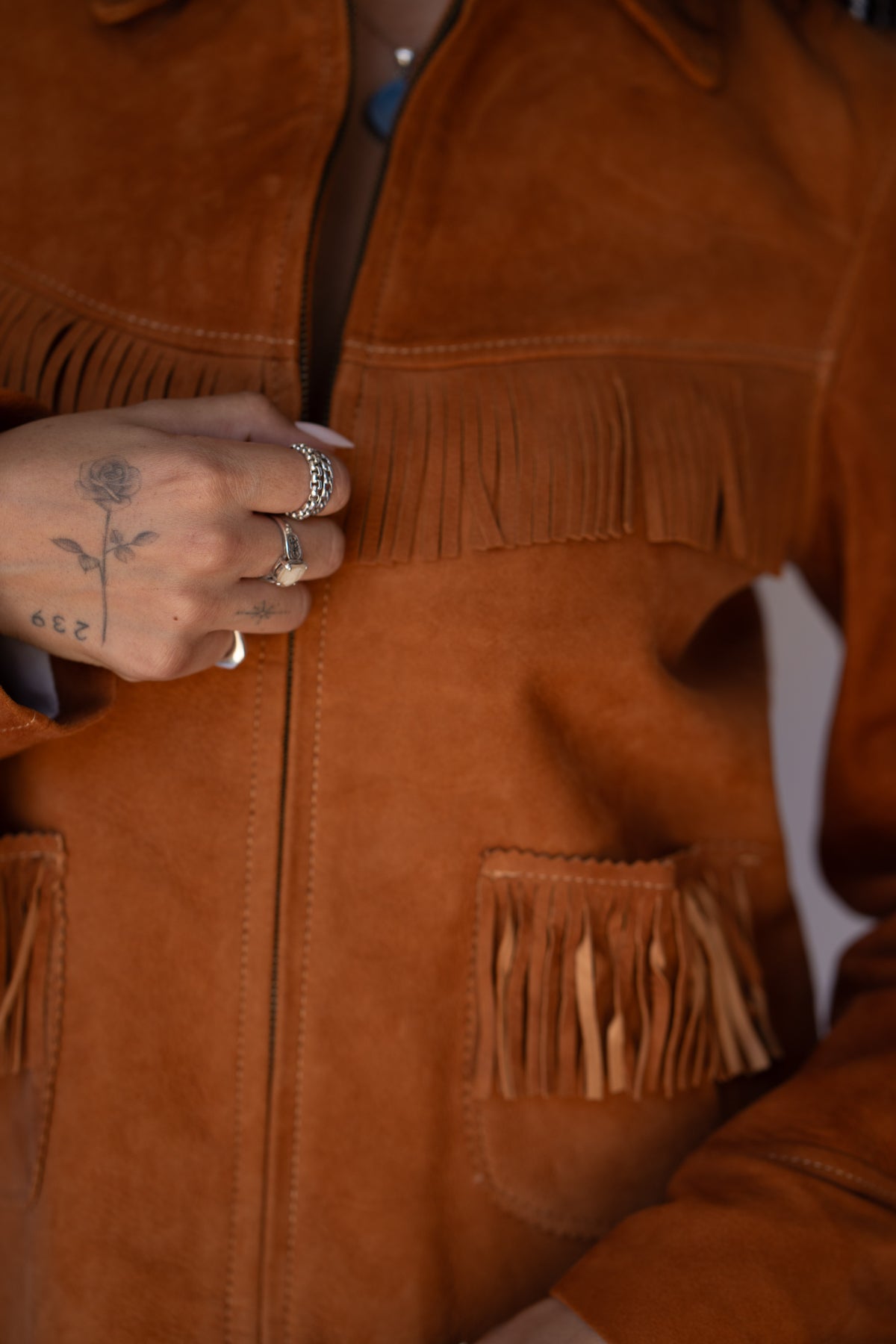 Detail of the H Bar C Omaha brown suede jacket zipper and fringe.