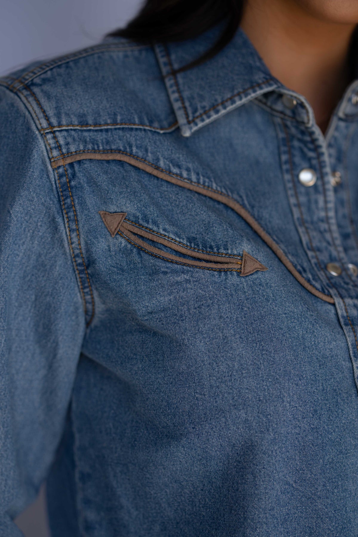 Close-up of the tan piped smile pocket with arrow tips on the Rustler x H Bar C women's denim cropped shirt.