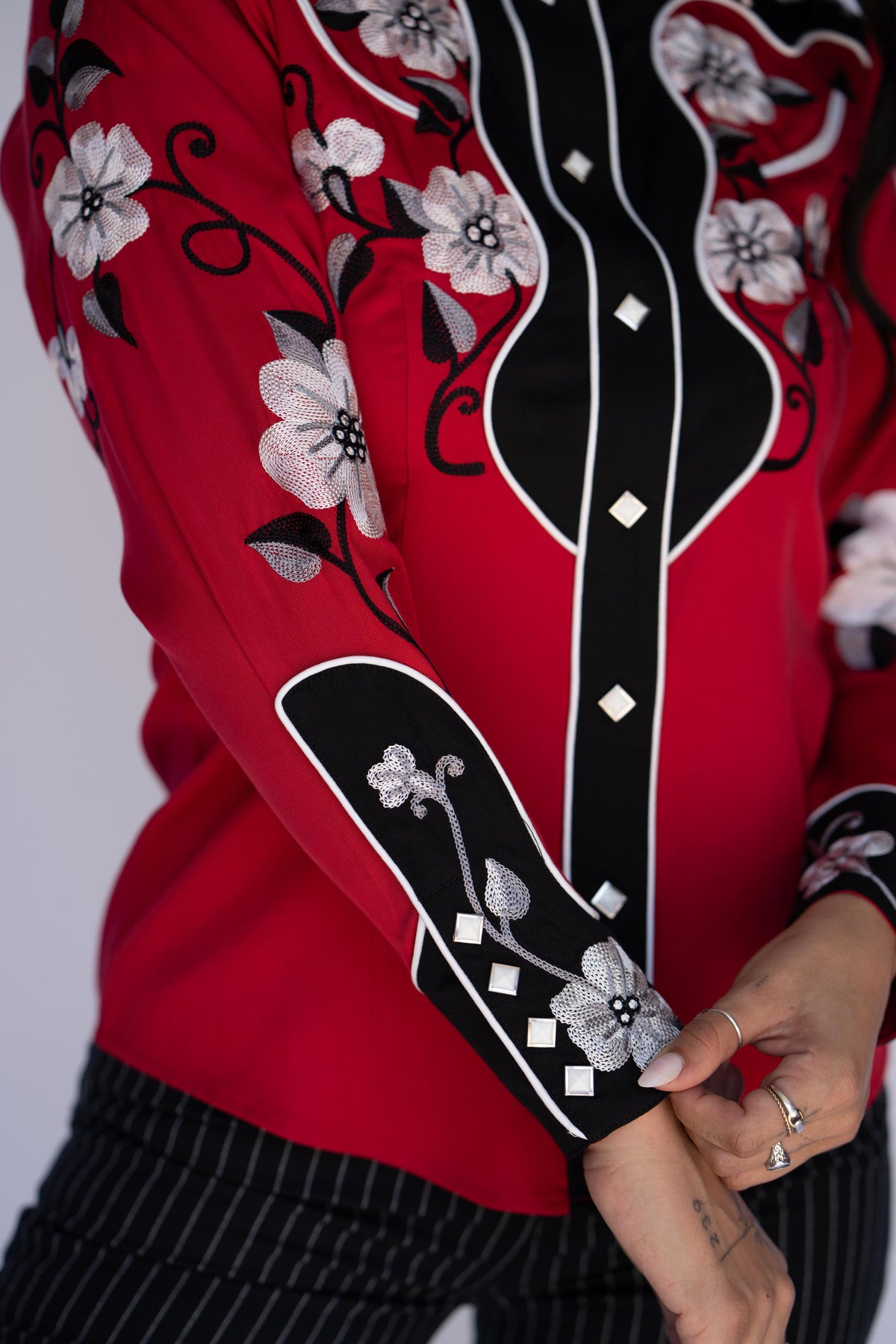 Sleeve and cuff detail of the H Bar C Santa Ana shirt with white floral embroidery on black and red.