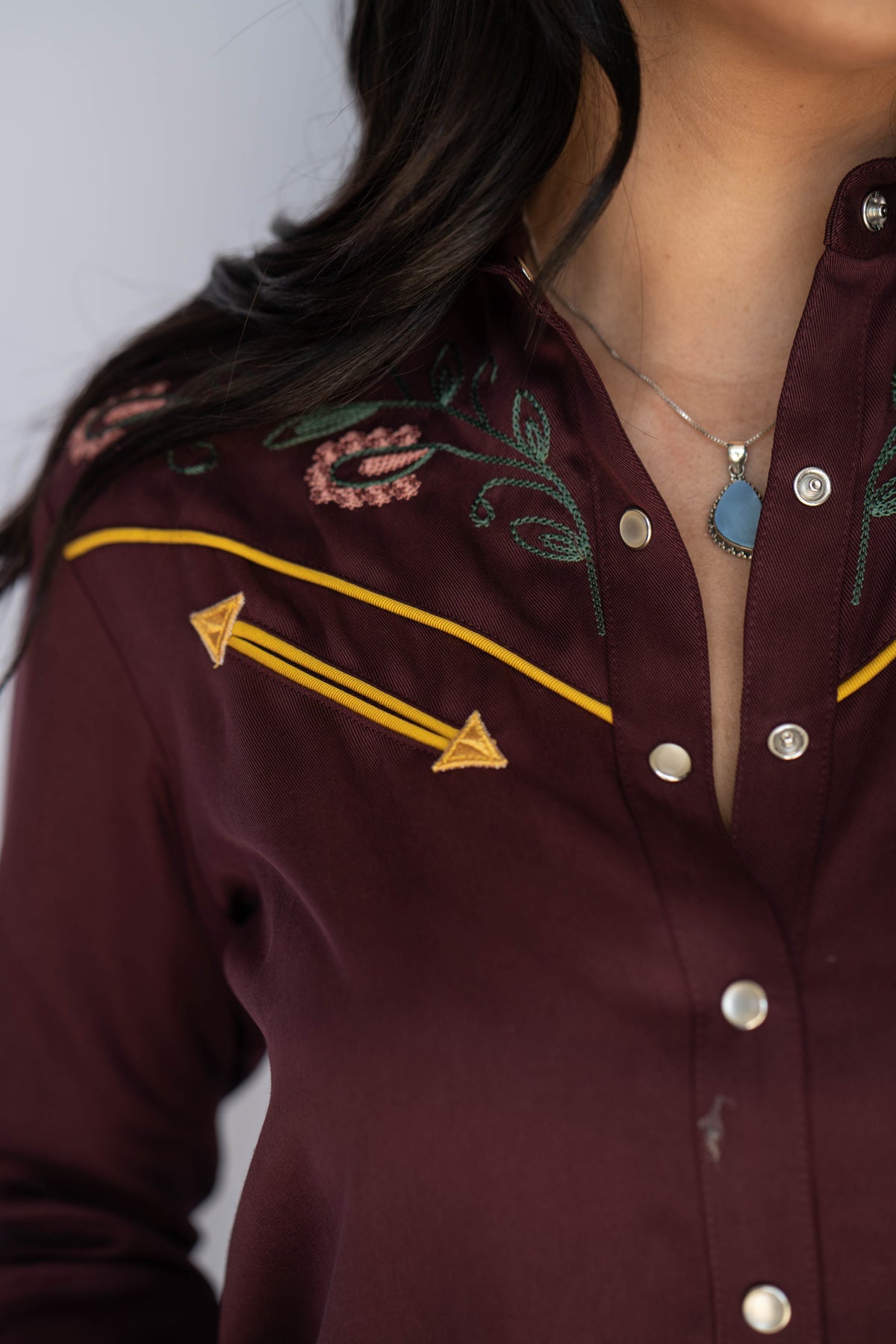 Close-up of the floral embroidery, yellow piping and snaps on the H Bar C Sedona maroon dress.