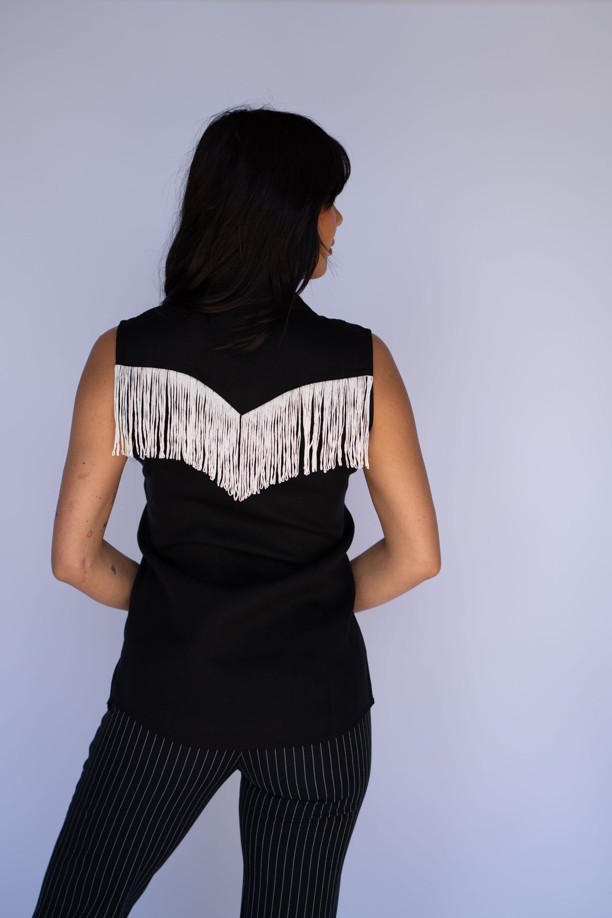 Back view of the H Bar C Tulsa women's black sleeveless shirt with white fringe across the shoulders.