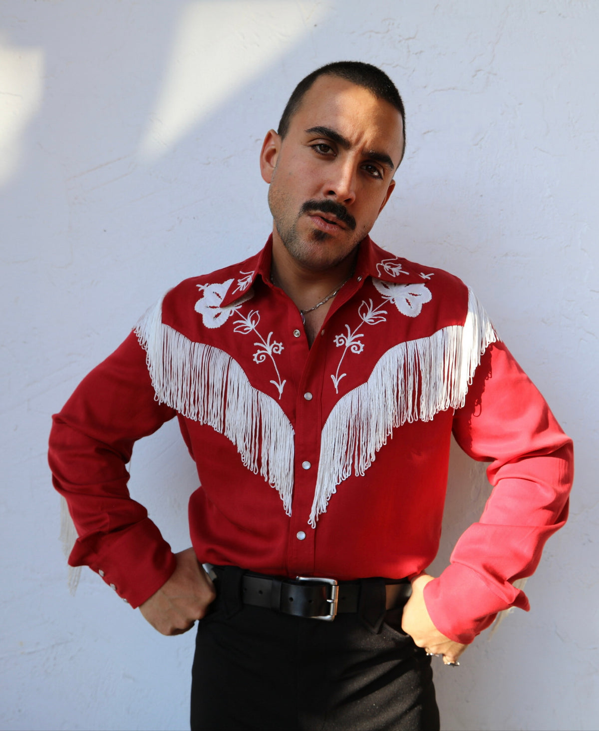 Man with hands on hips in the H Bar C Taos red fringe western shirt with black pants.
