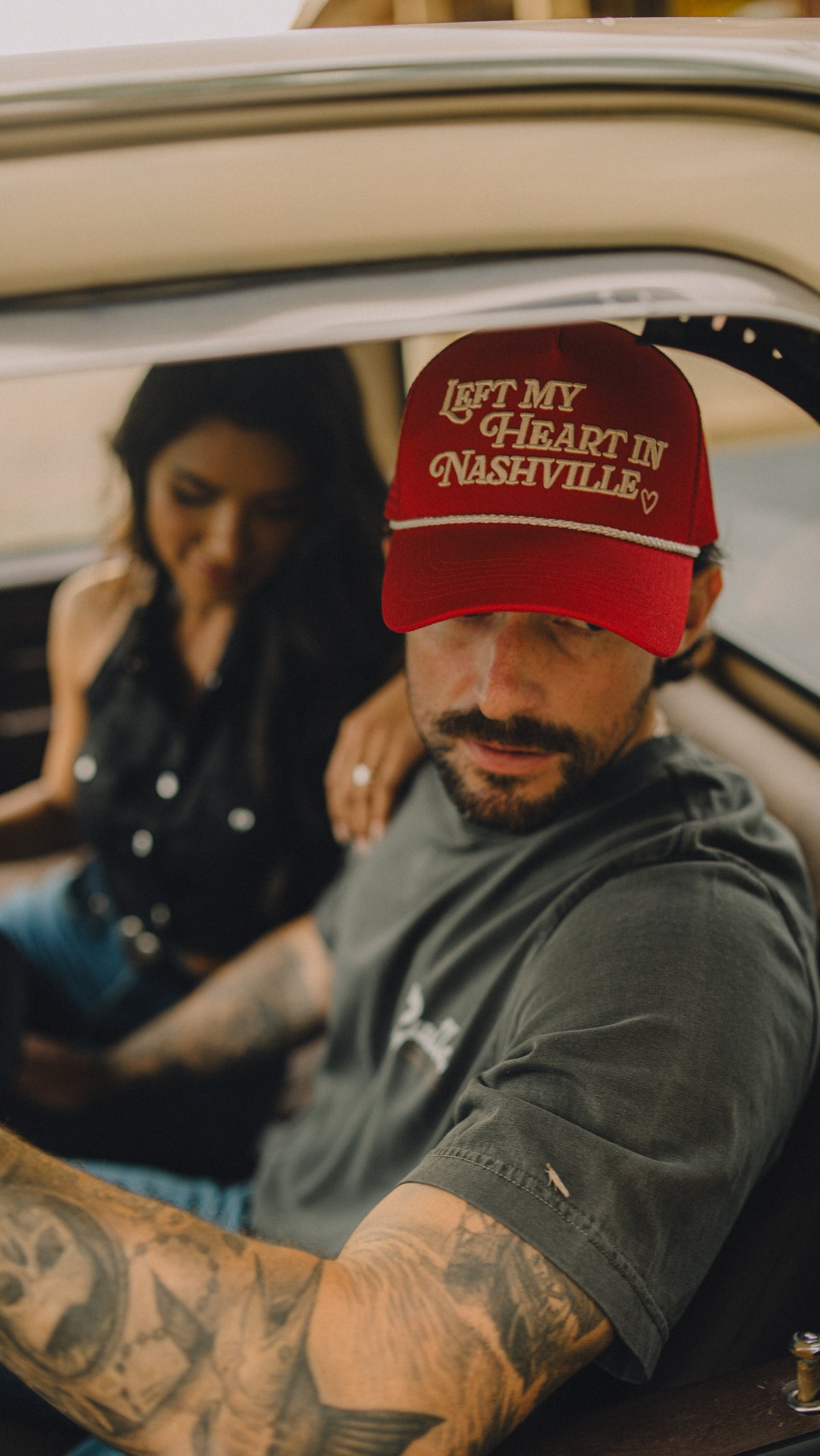 Man in a vintage truck wearing the red H Bar C x Rustler Left My Heart in Nashville trucker hat.