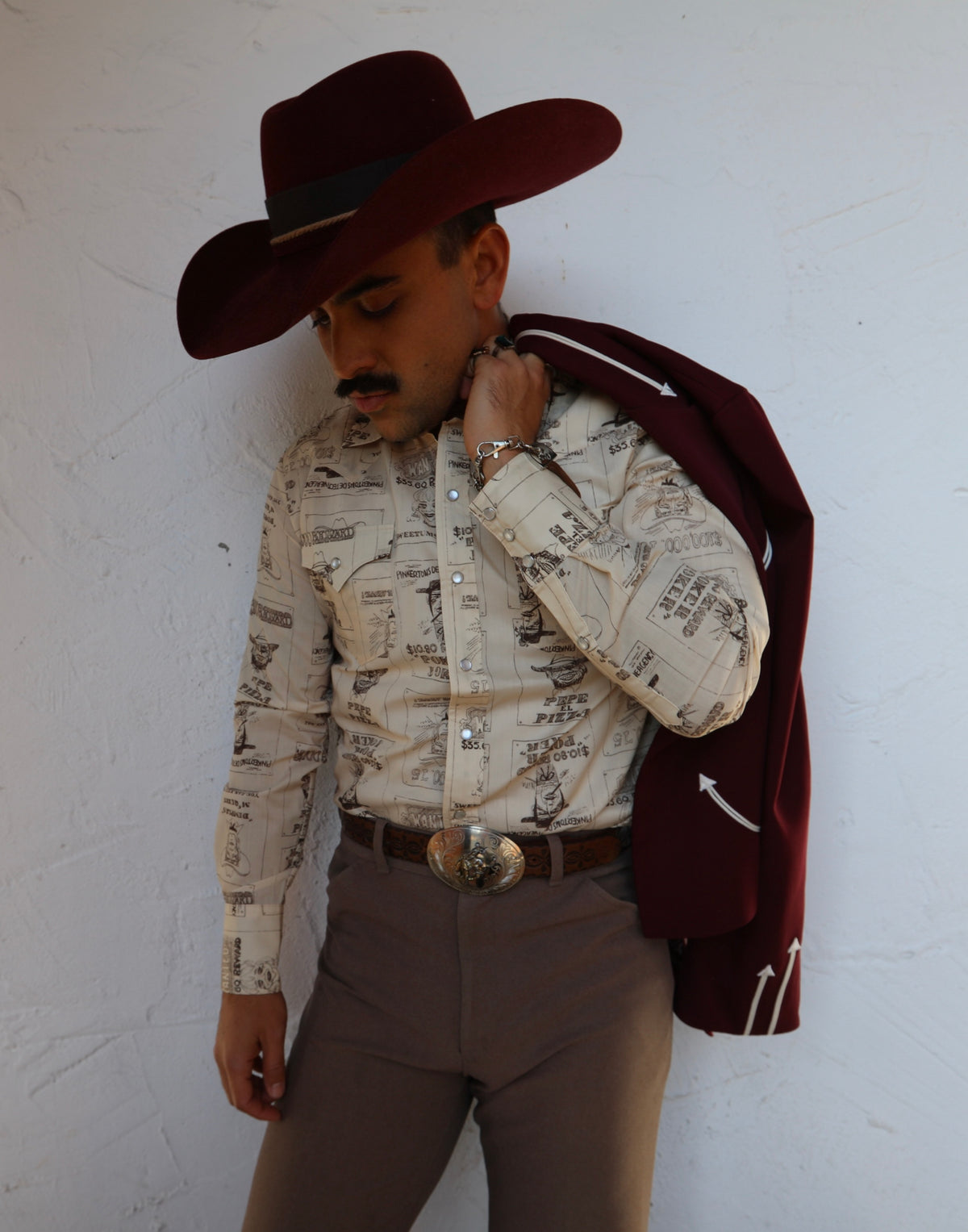 Man in a cowboy hat with a jacket over his shoulder wearing the H Bar C Tumbleweed beige shirt.