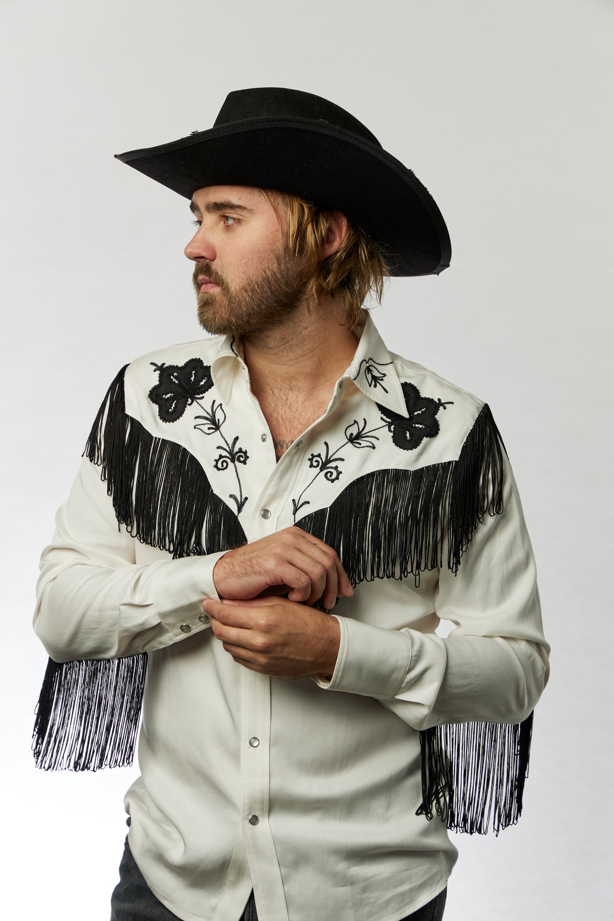 Man fastening the cuff of the H Bar C Taos men's white fringe western shirt.