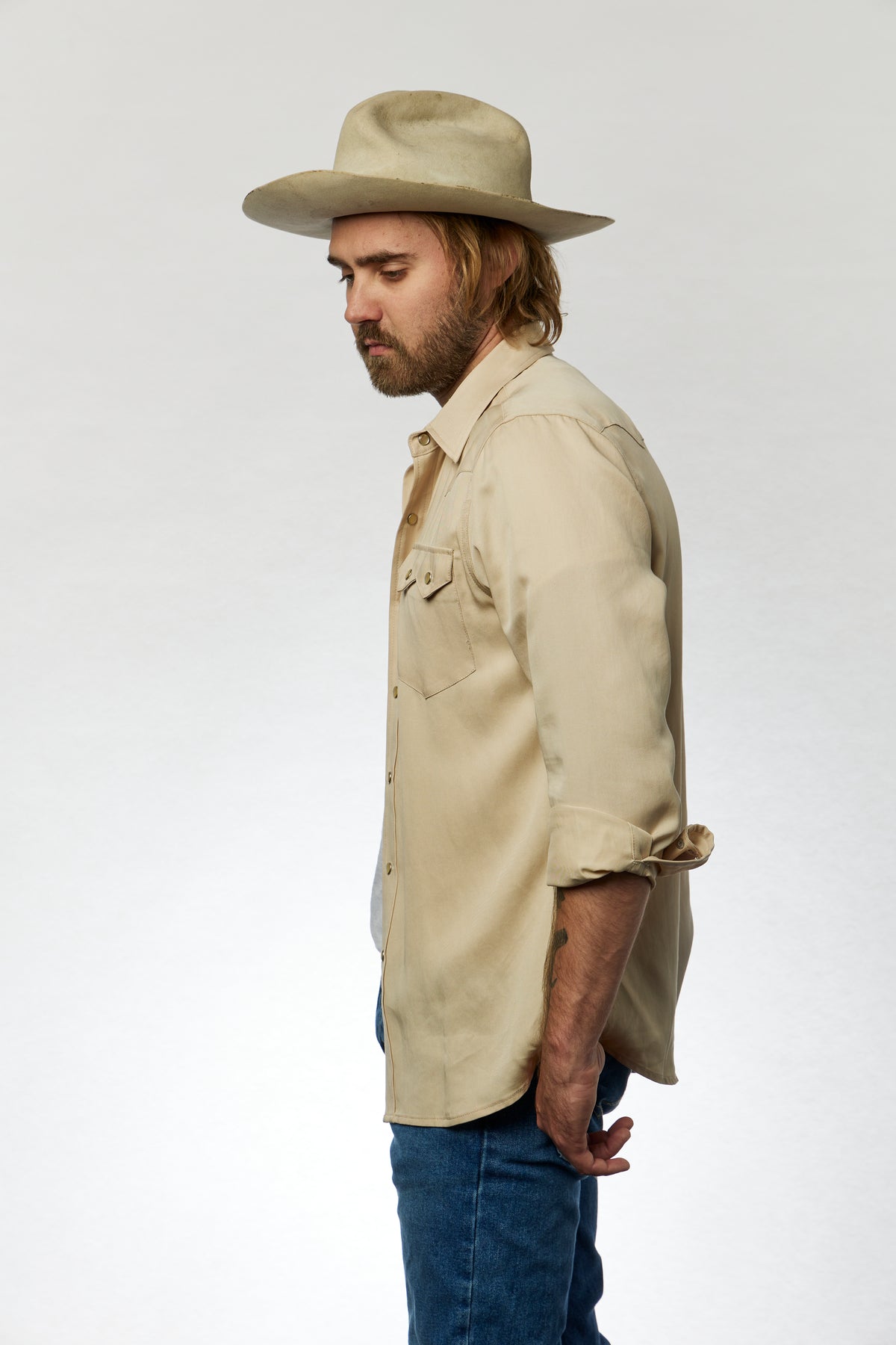 Side view of a man in a cowboy hat wearing the H Bar C Kansas City beige western shirt with jeans.