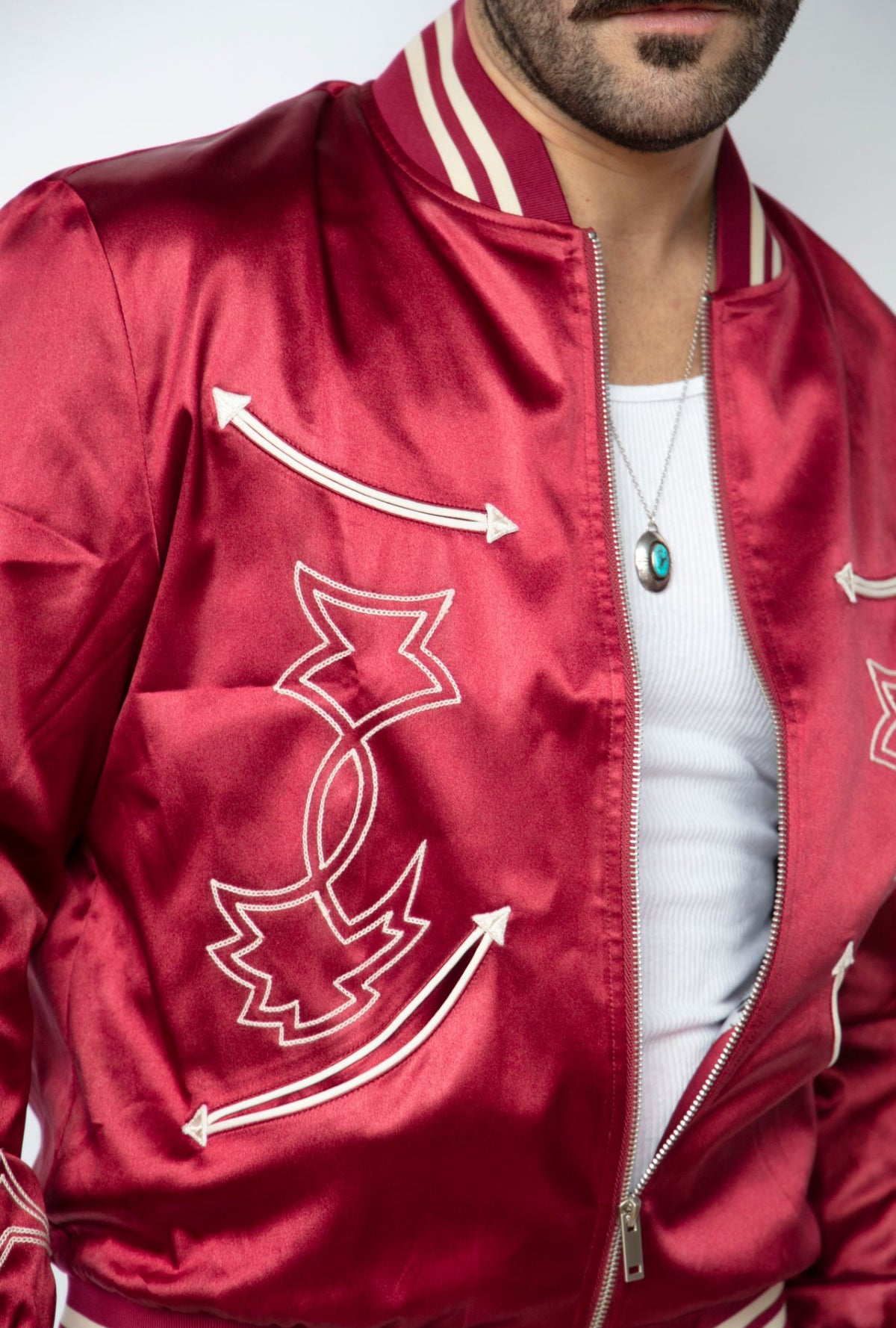 Close-up of the white arrow and boot stitch embroidery on the H Bar C Odessa red satin tour jacket.