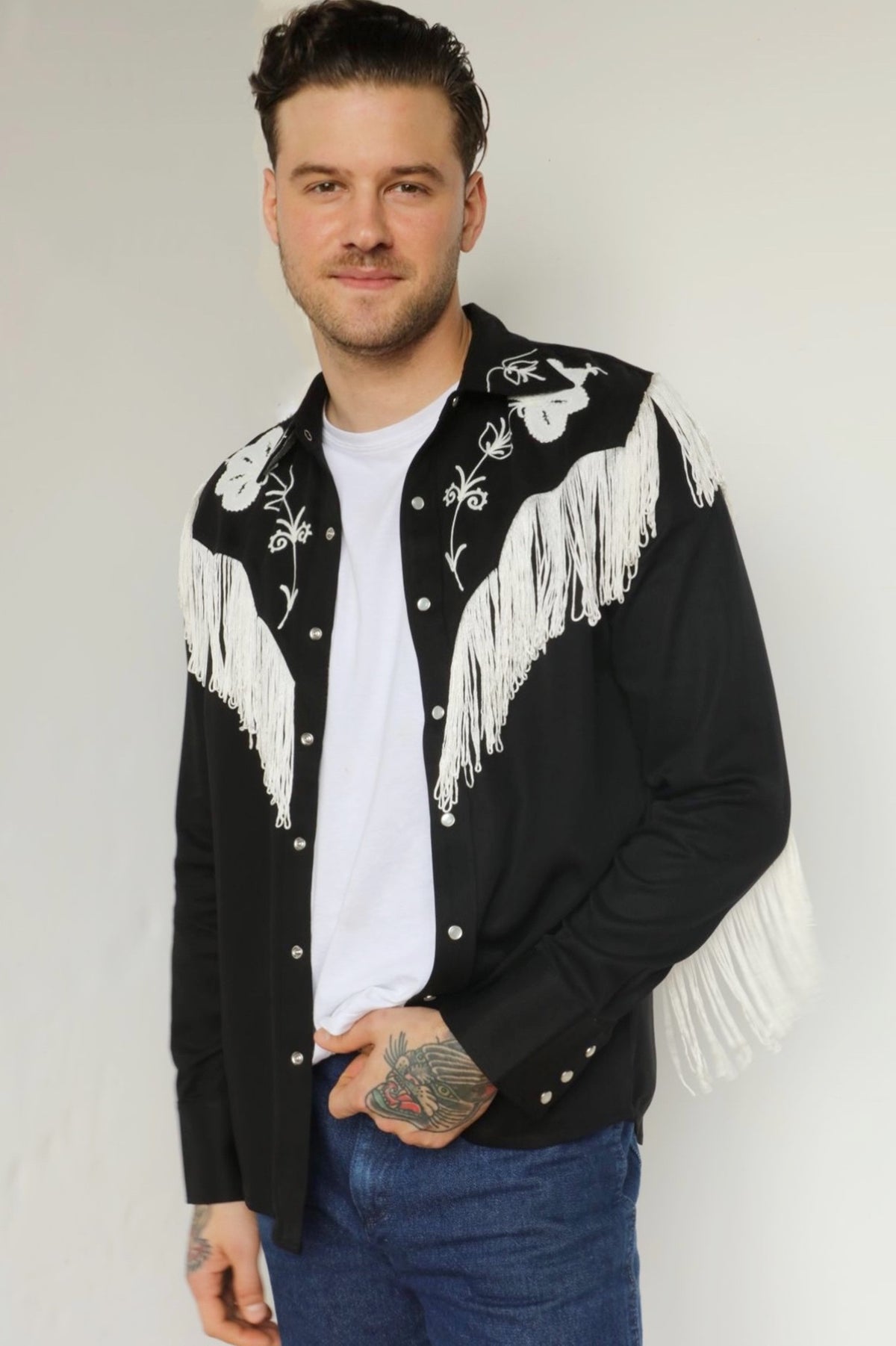 Man snapping the H Bar C Taos men's shirt in black and white with white fringe and embroidered yoke, worn with jeans.