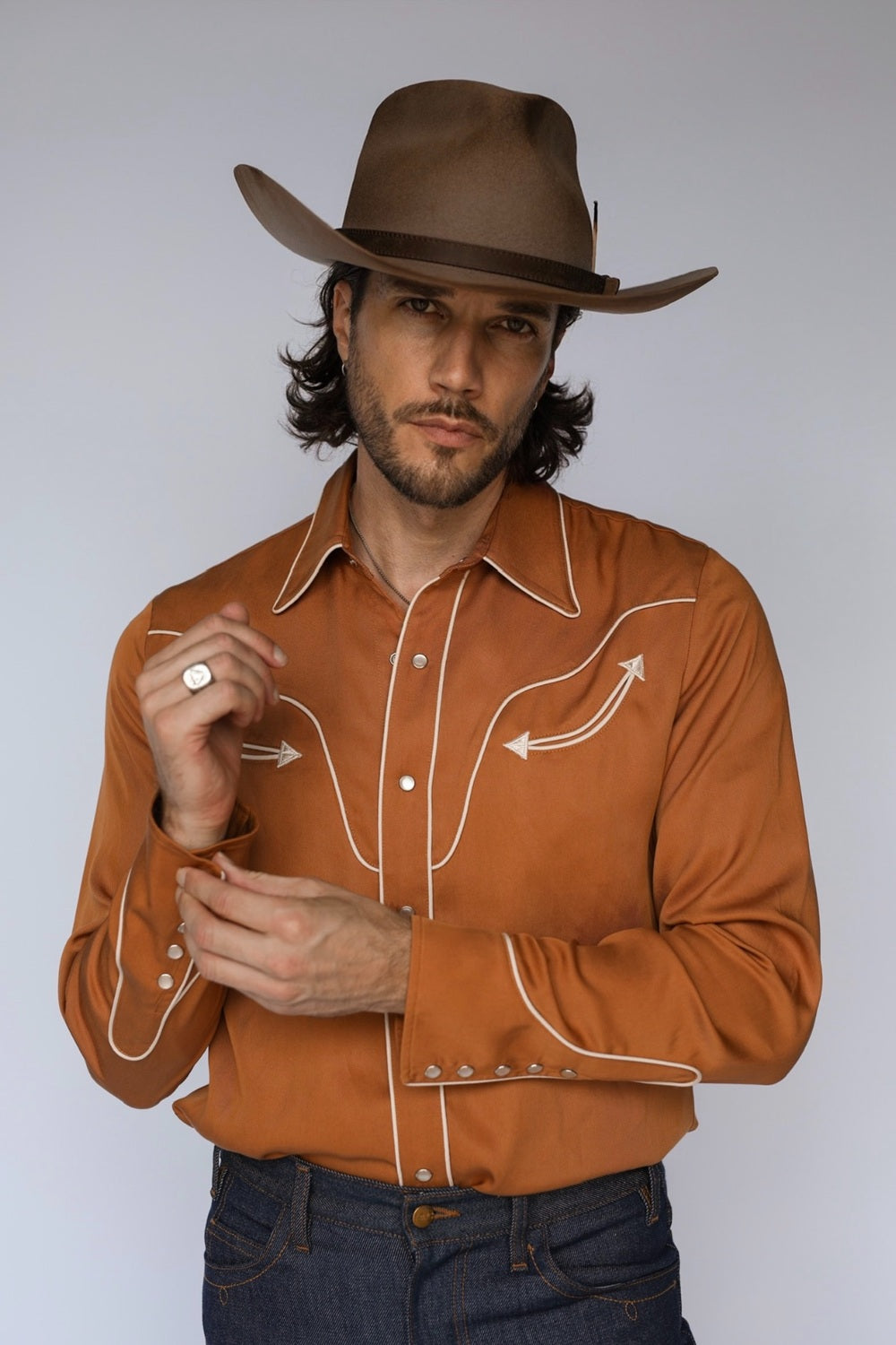 Man in a brown cowboy hat wearing the H Bar C San Fernando men's shirt in burnt orange with cream piping and arrow details, a vintage H Bar C classic.