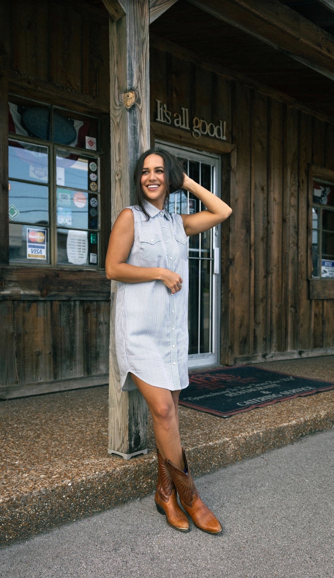 Woman in cowboy boots wearing the H Bar C Palm Beach striped shirt dress outside a wooden western storefront.