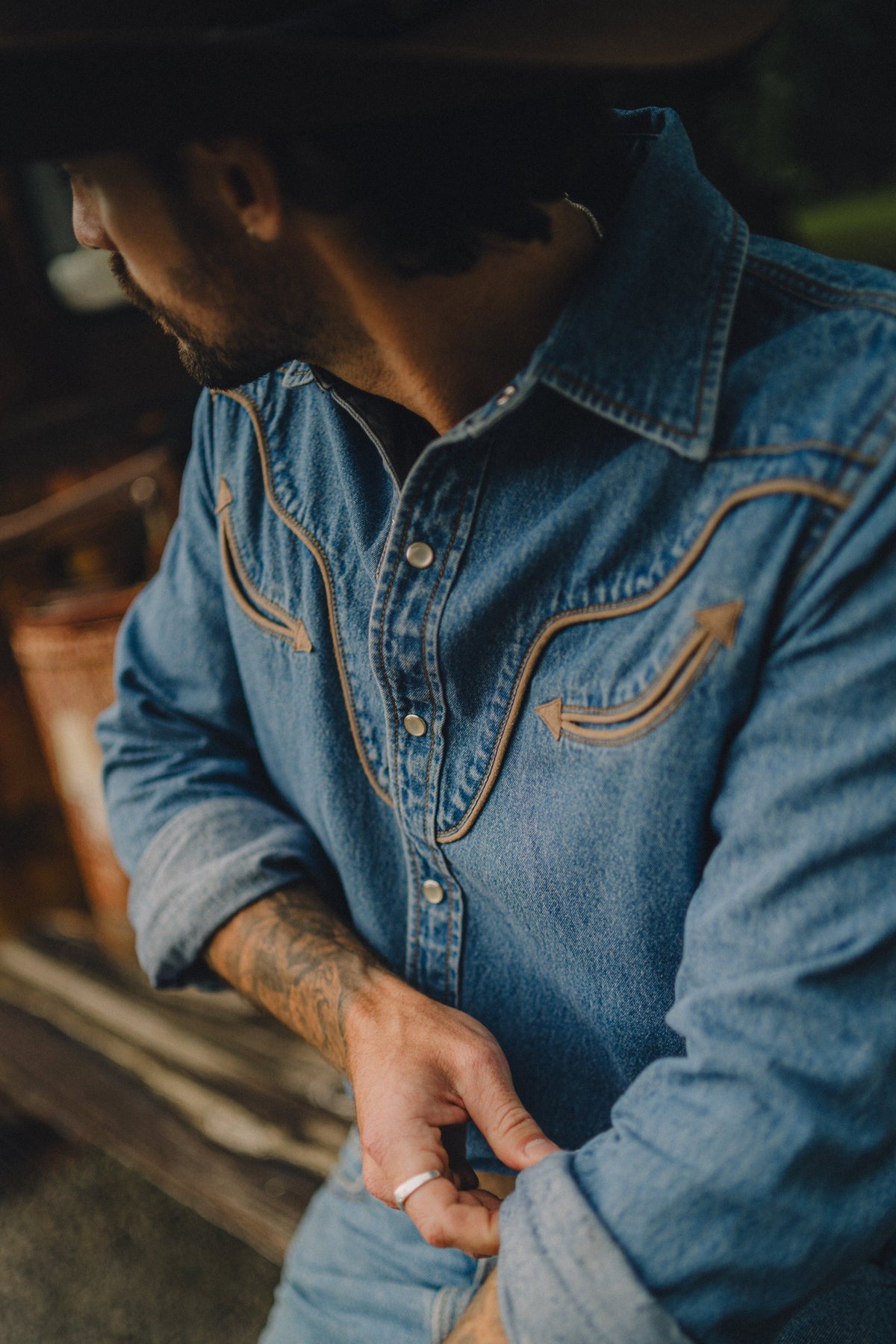 Close-up of the piped smile pocket and snaps on the Rustler x H Bar C men's denim shirt.
