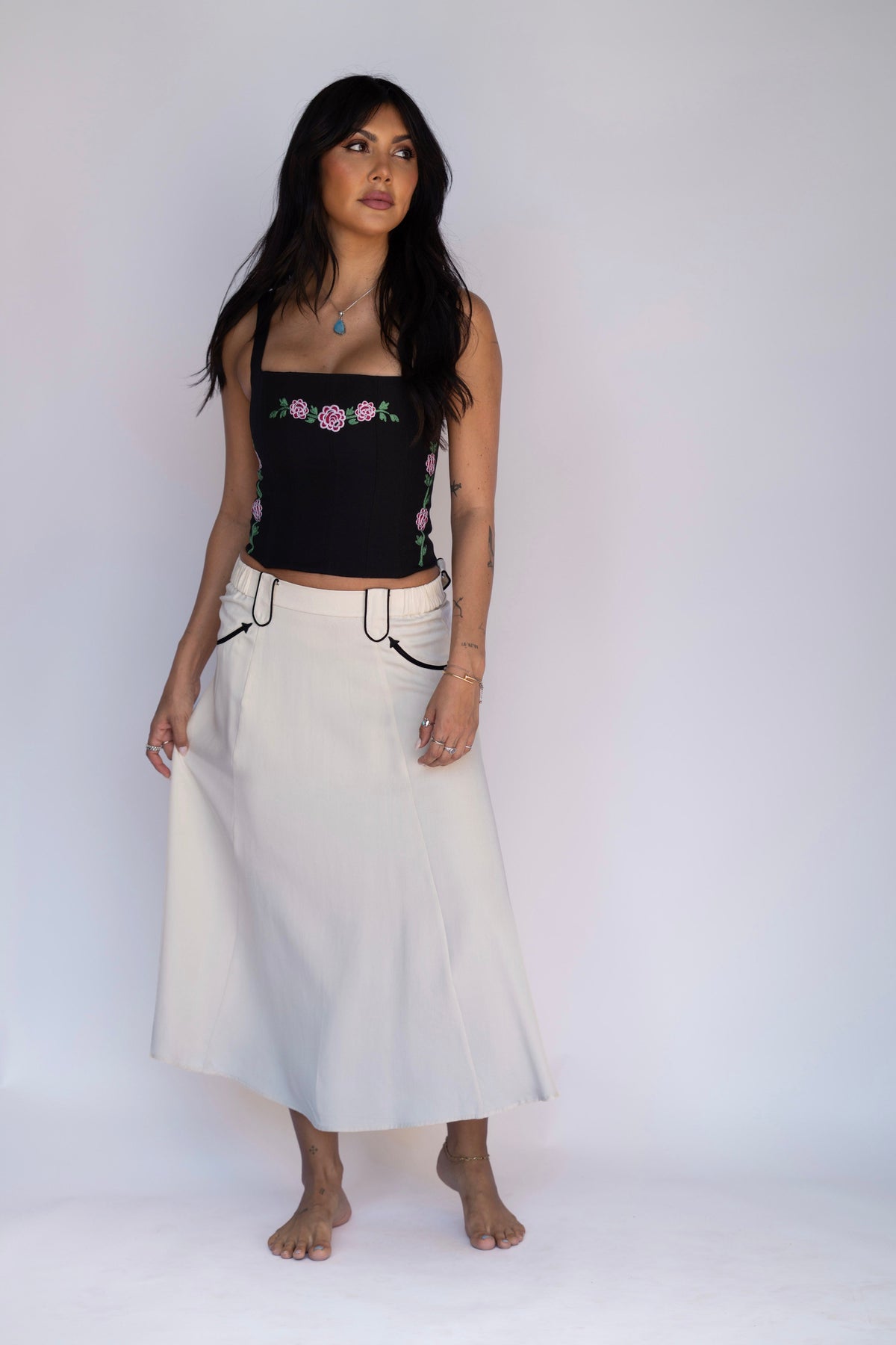 Woman wearing the H Bar C Santa Fe women's skirt in off white with black piping, styled with an embroidered black corset.