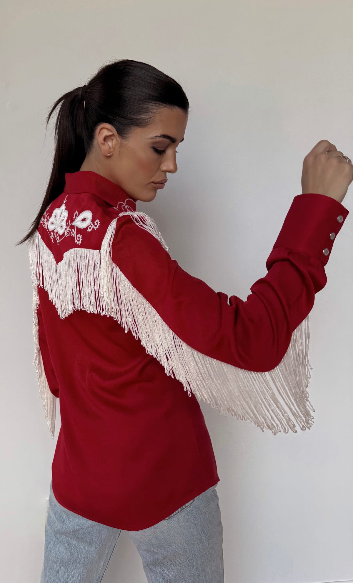 Side view of the H Bar C Taos women's red shirt showing white sleeve fringe.