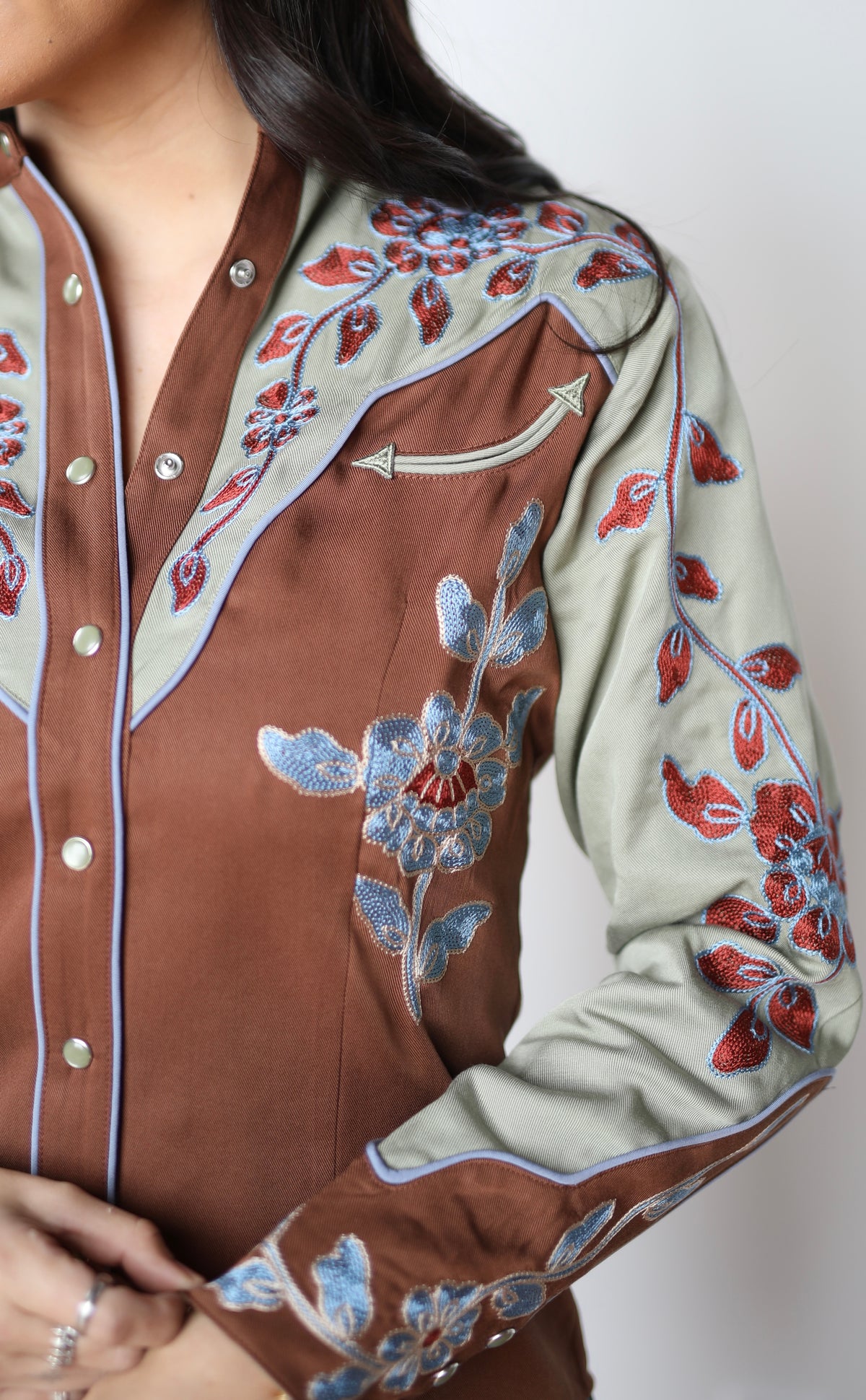 Close-up of the sage yoke and red floral chain stitch on the H Bar C San Antonio women's brown rodeo shirt.