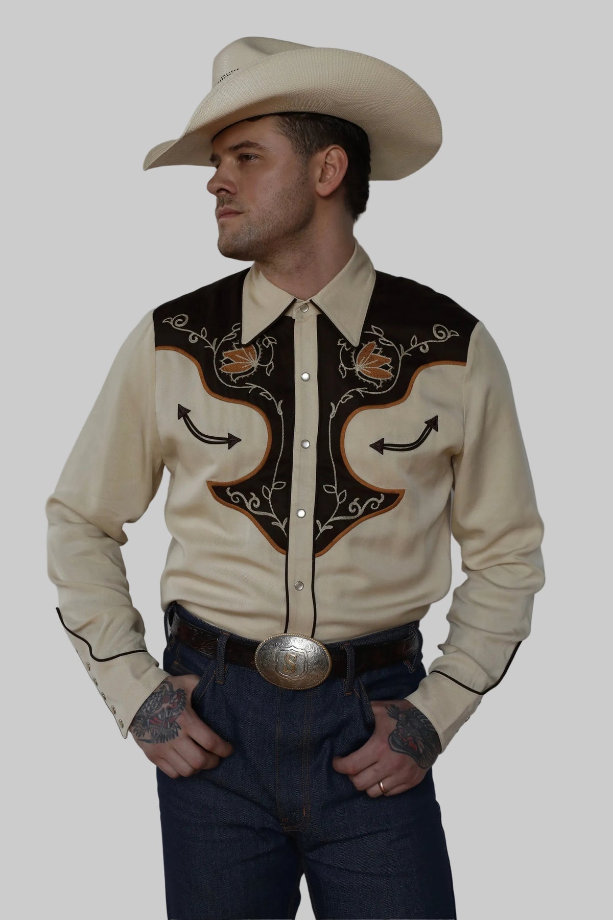 Man in a cream cowboy hat wearing the H Bar C Santa Barbara men's shirt in cream with brown embroidered yokes, a 1970s western style.