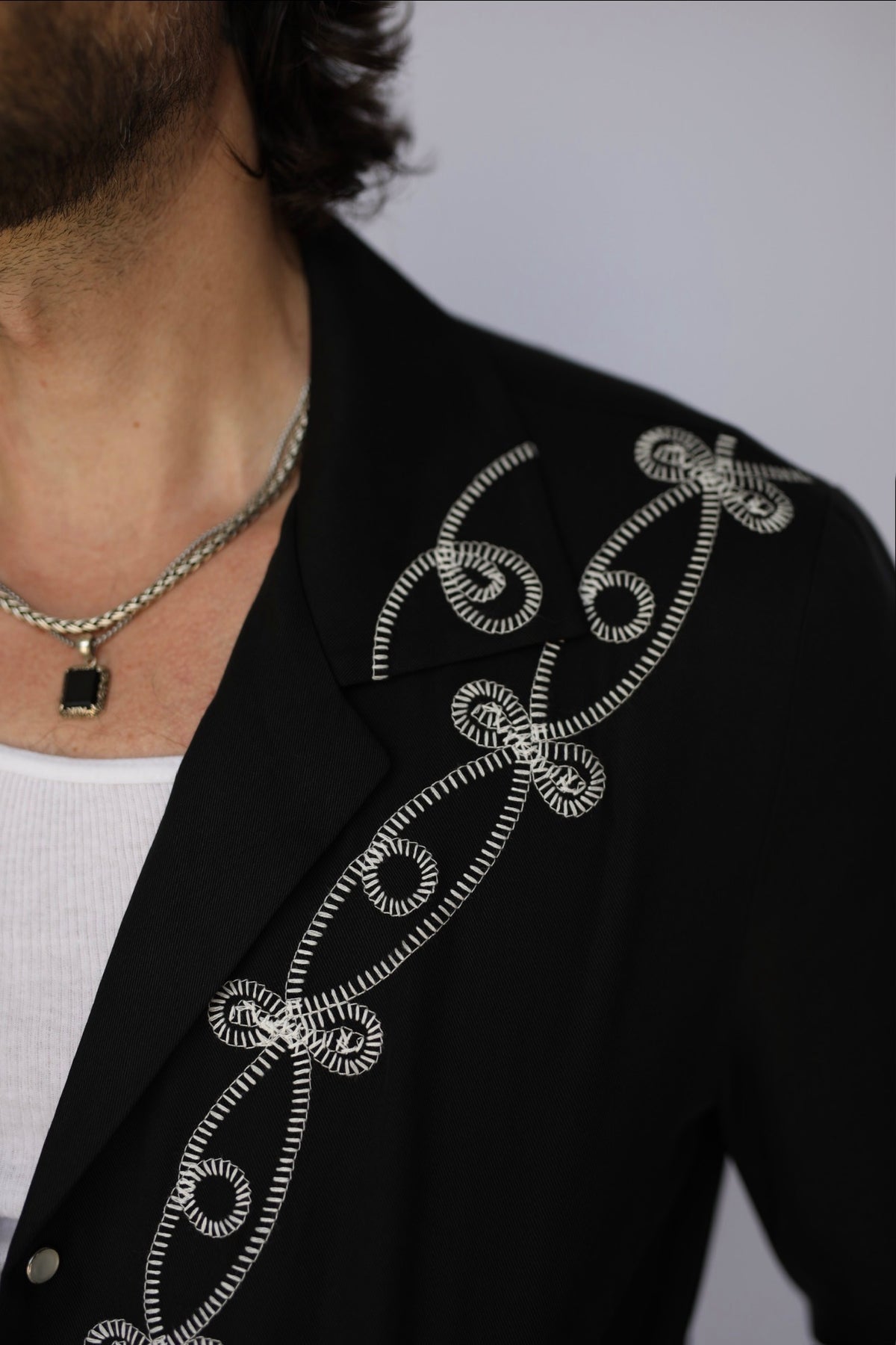 Close-up of the white swirl embroidery on the shoulder and chest of the H Bar C El Patrón Bolero jacket.