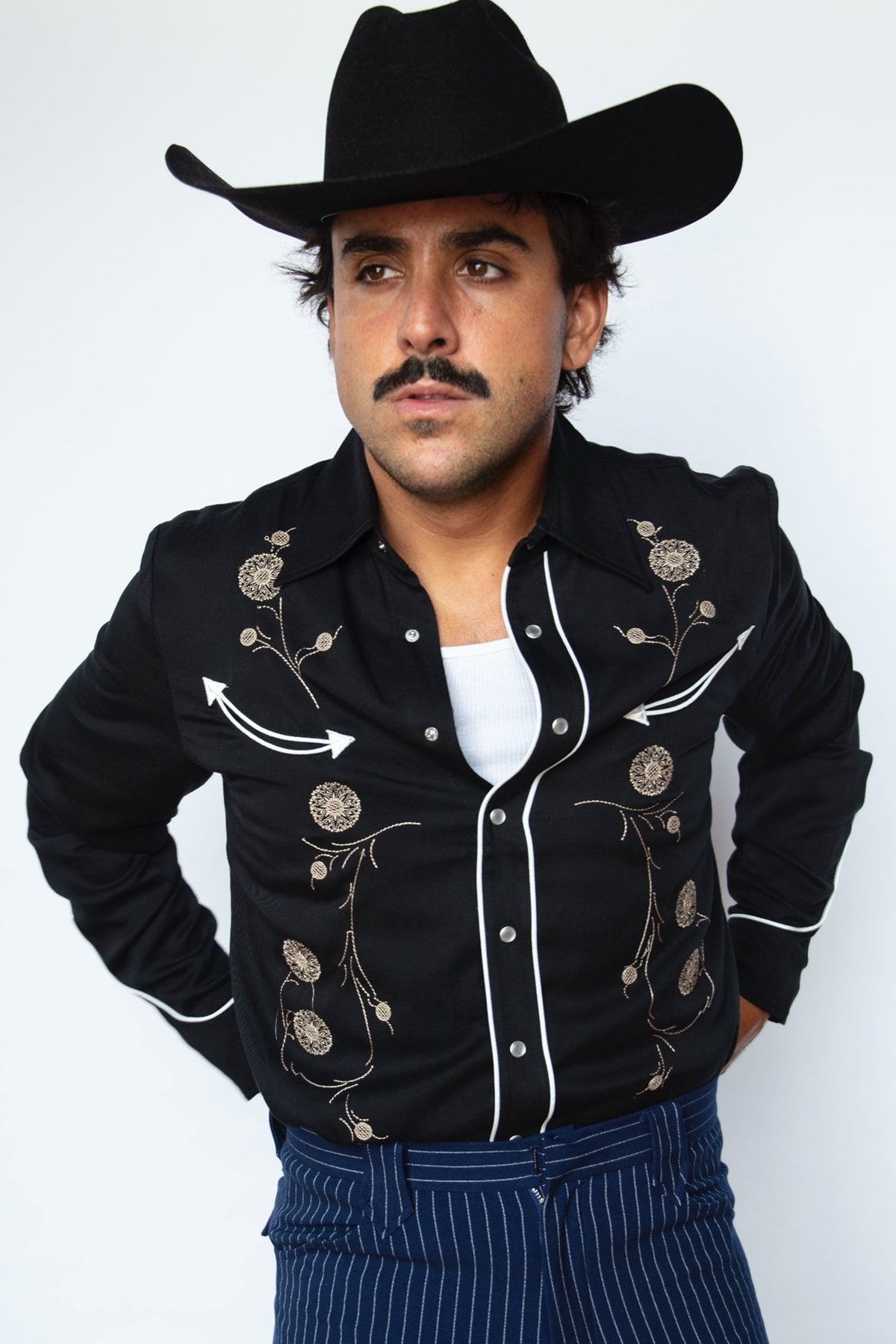 Man in a black cowboy hat wearing the HBarC x Gibson J-200 men's shirt in black Tencel with chain stitch embroidery and white piping.