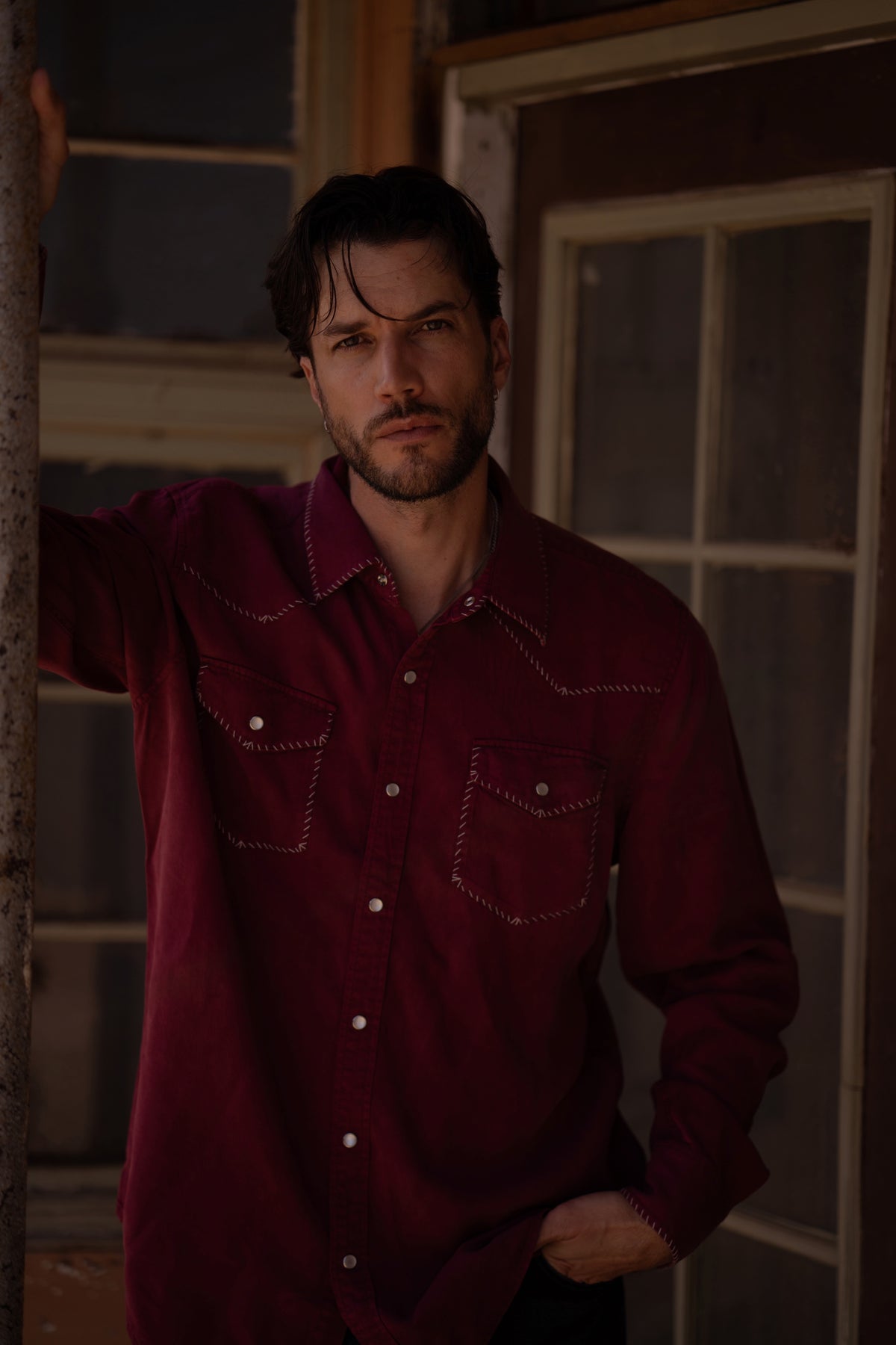 Man wearing the H Bar C Brooklyn men's wine western shirt in a rustic setting.