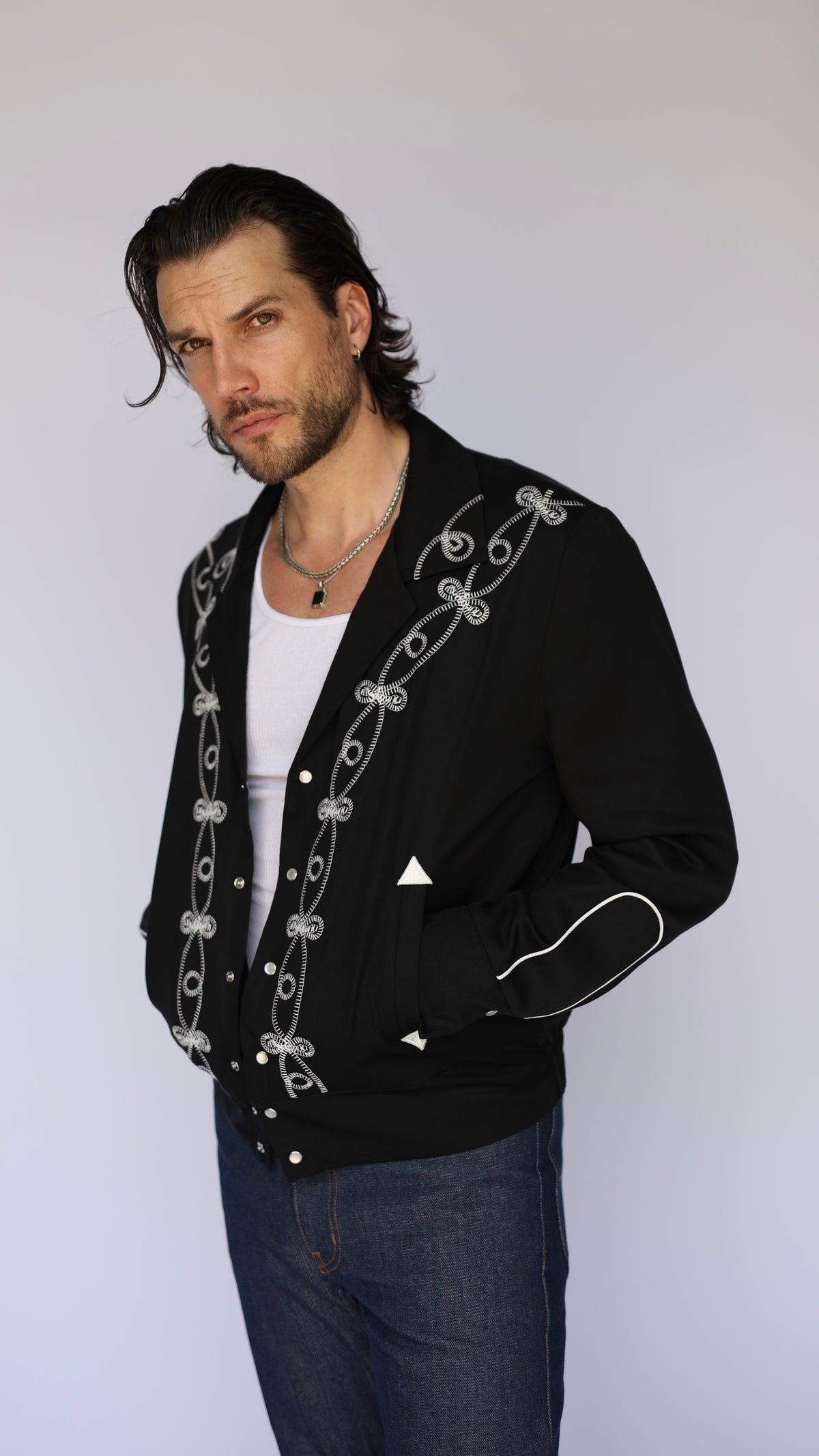 Front view of the H Bar C Bolero El Patrón black and white embroidered western jacket with jeans.