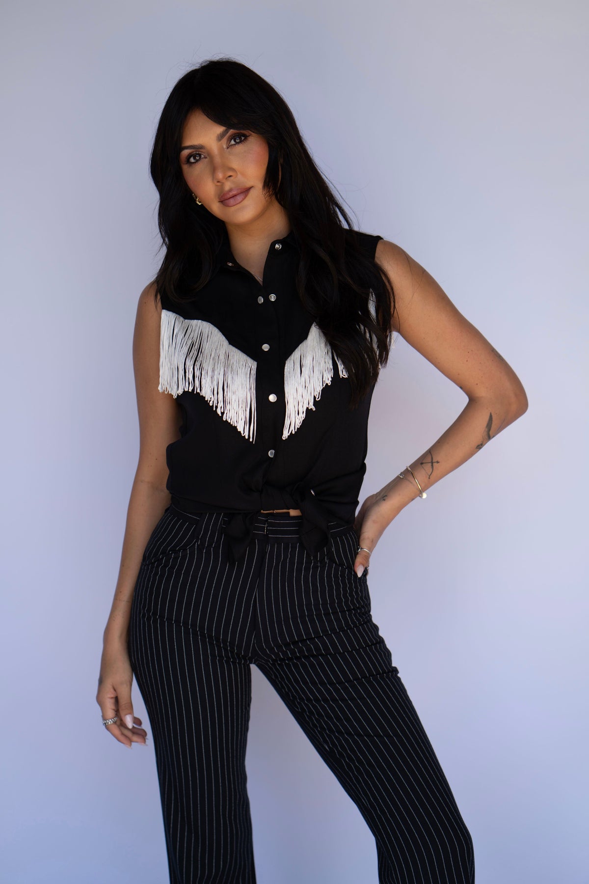 Woman with hand on hip in the H Bar C Tulsa black fringe sleeveless western top.