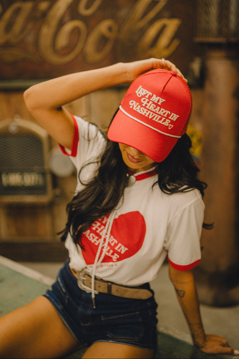 Woman wearing the red H Bar C x Rustler Left My Heart in Nashville trucker hat with the matching ringer tee.