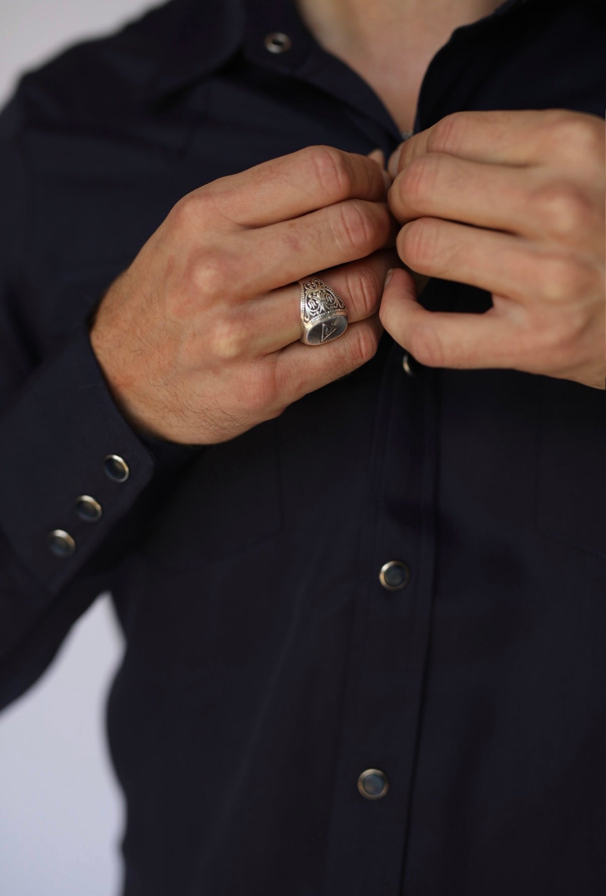 Hands fastening the snap placket of the H Bar C Denver navy Tencel western shirt.