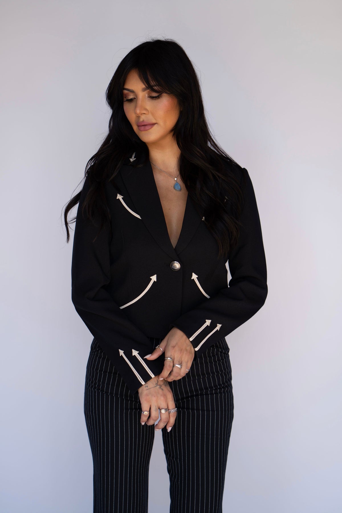 Model in the H Bar C Calamity women's black jacket with cream embroidered arrows and pinstripe pants.