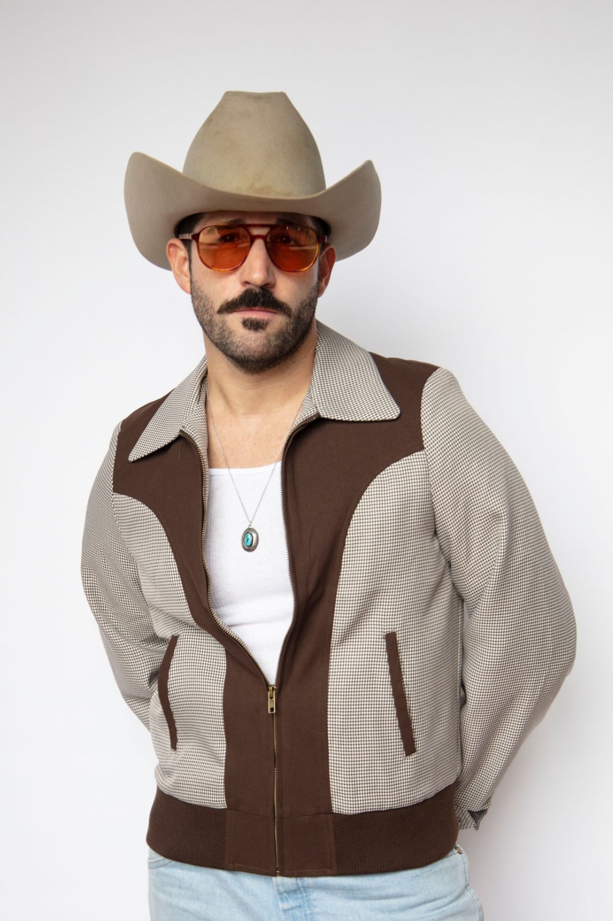 Man in a cowboy hat wearing the H Bar C Kentucky unisex jacket in espresso houndstooth with chocolate suede panels, a 1950s H Bar C reproduction.