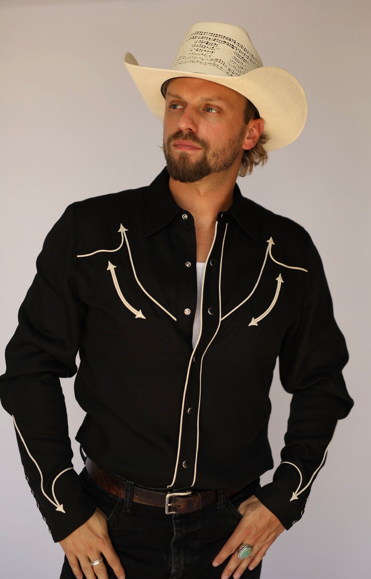 Man in a straw cowboy hat wearing the H Bar C Reno black western shirt with off-white piped smile yokes and arrows.