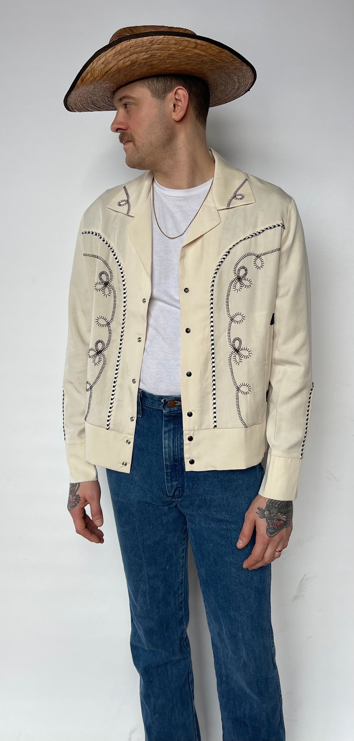 Front view of the H Bar C Bolero off-white jacket worn open with jeans and a cowboy hat.