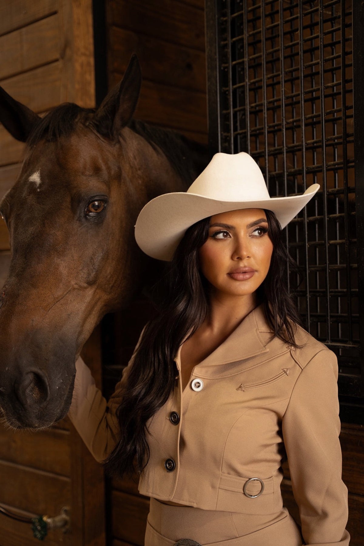 Woman beside a horse in a stable wearing the H Bar C Raleigh tan cropped western jacket.