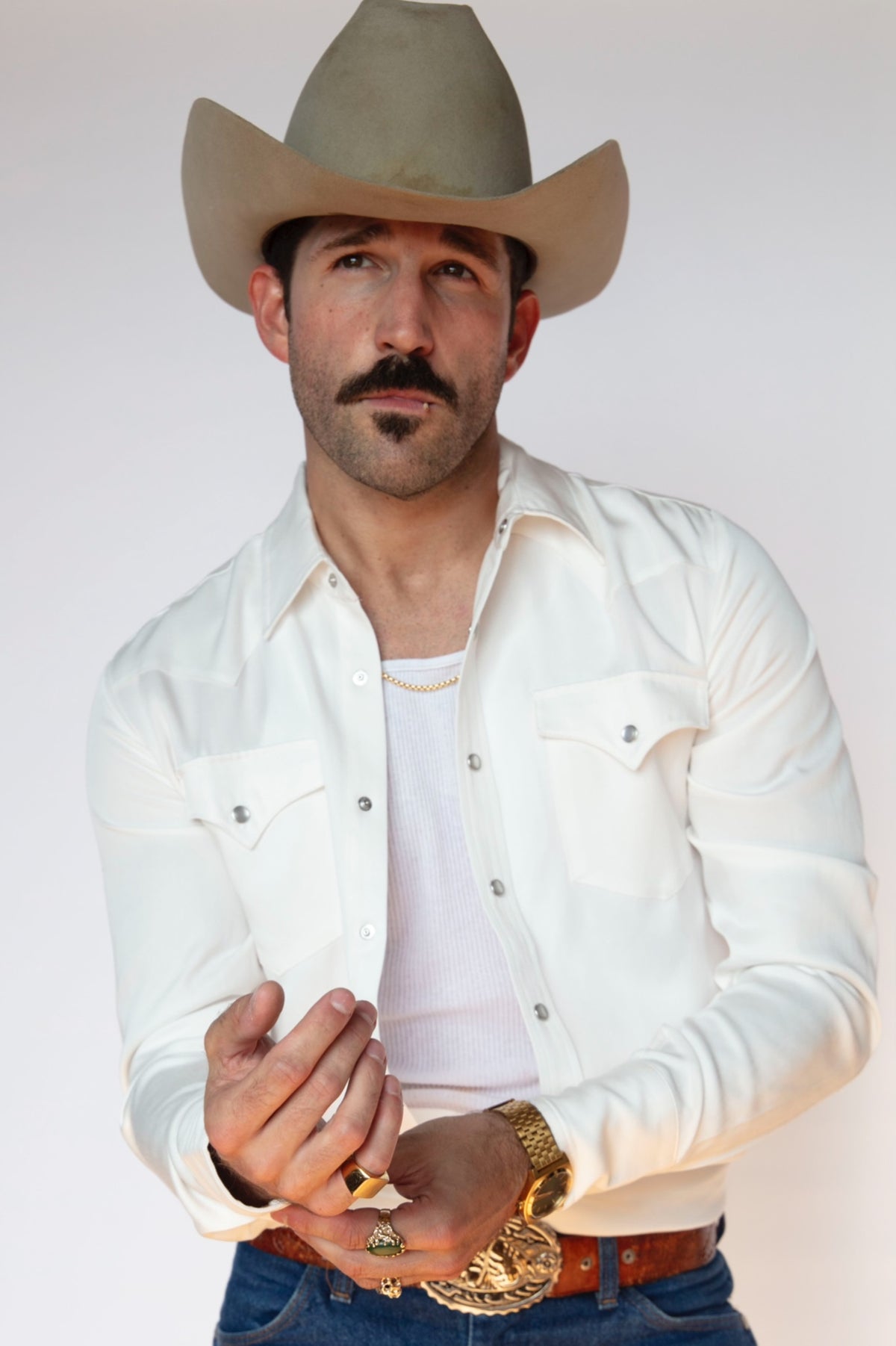 H Bar C Denver men's white western shirt worn open at the collar with jeans, a gold buckle, and a felt cowboy hat.