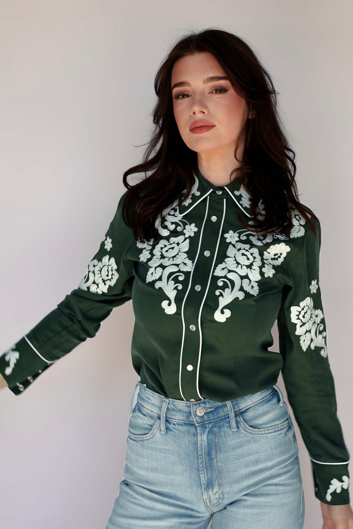 Woman posing in the H Bar C Fort Worth green floral embroidered western shirt.