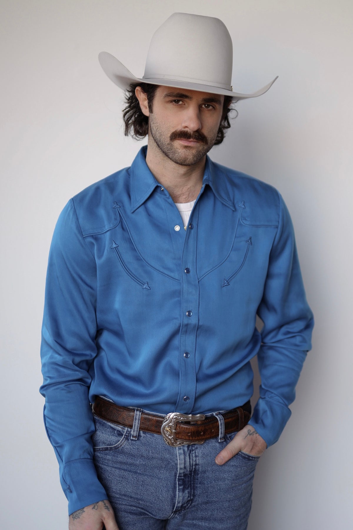 Man in a cream cowboy hat wearing the H Bar C Reno shirt in royal blue with tonal piping and pearl snaps.