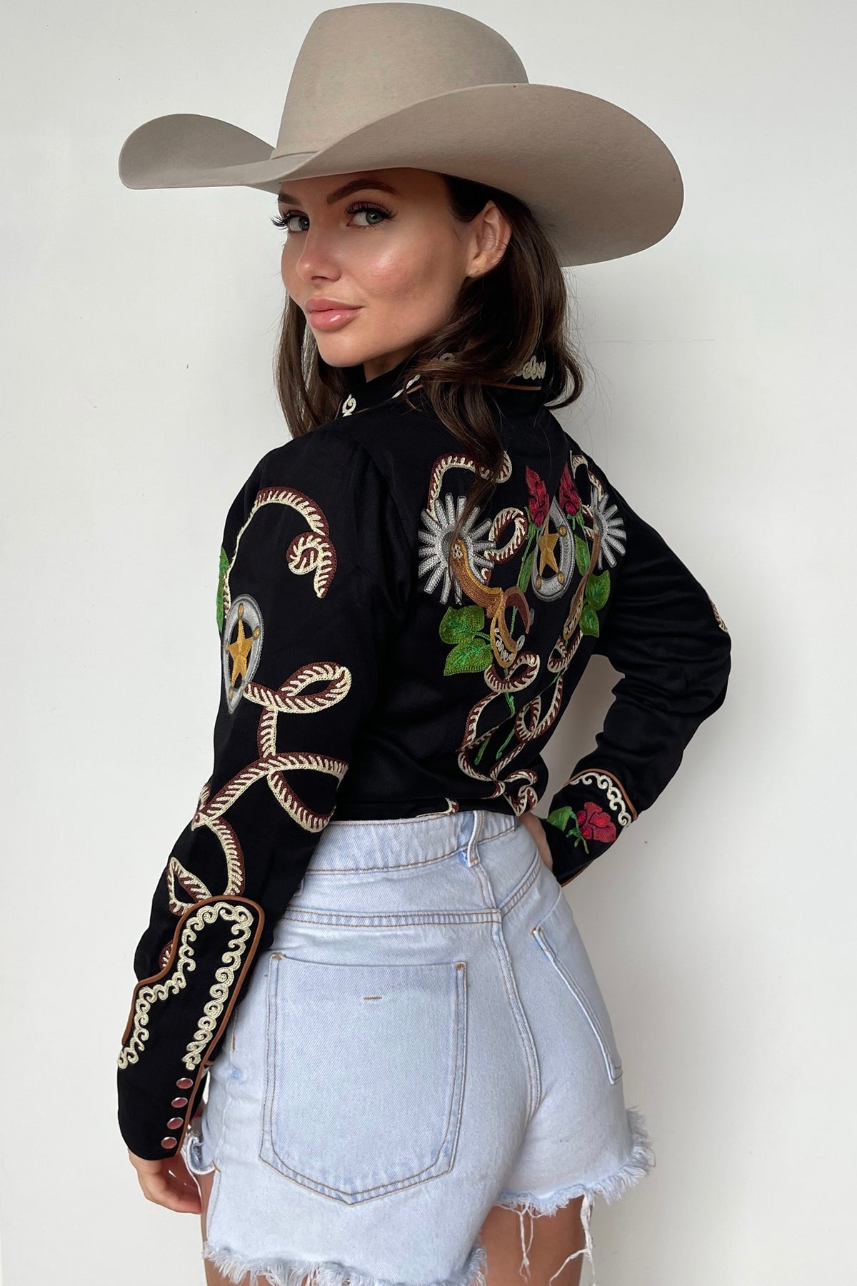 Side view of a woman in a cowboy hat wearing the H Bar C Catalina women's shirt in black with extensive chain stitch rope and rose embroidery.