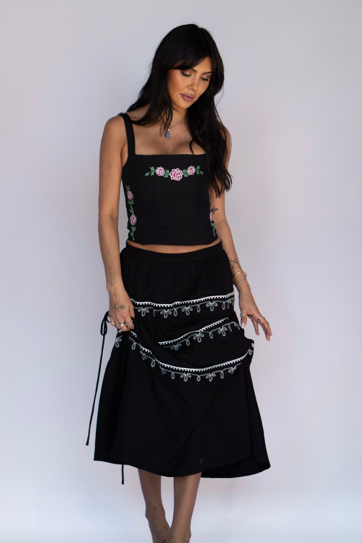 Full length view of the H Bar C Canterbury black corset with rose embroidery and a black tiered skirt with white trim.