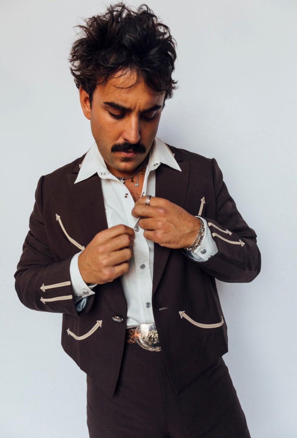 Man buttoning the H Bar C Calamity chocolate western jacket over a white shirt.