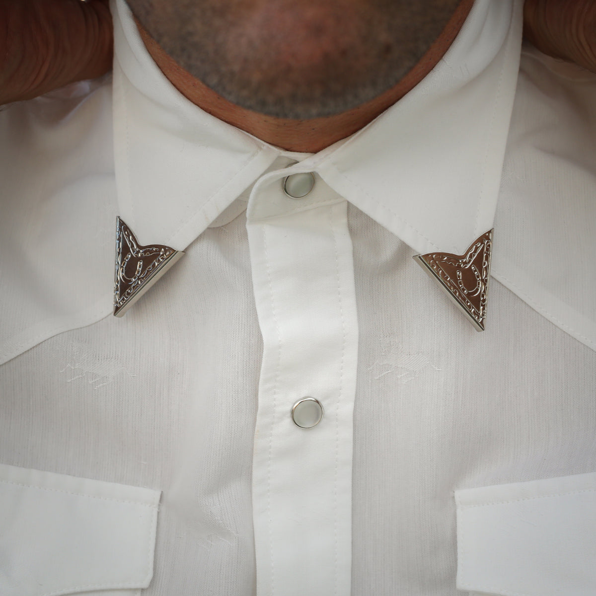 Close-up of H Bar C screw-on engraved collar tips on a white snap shirt.