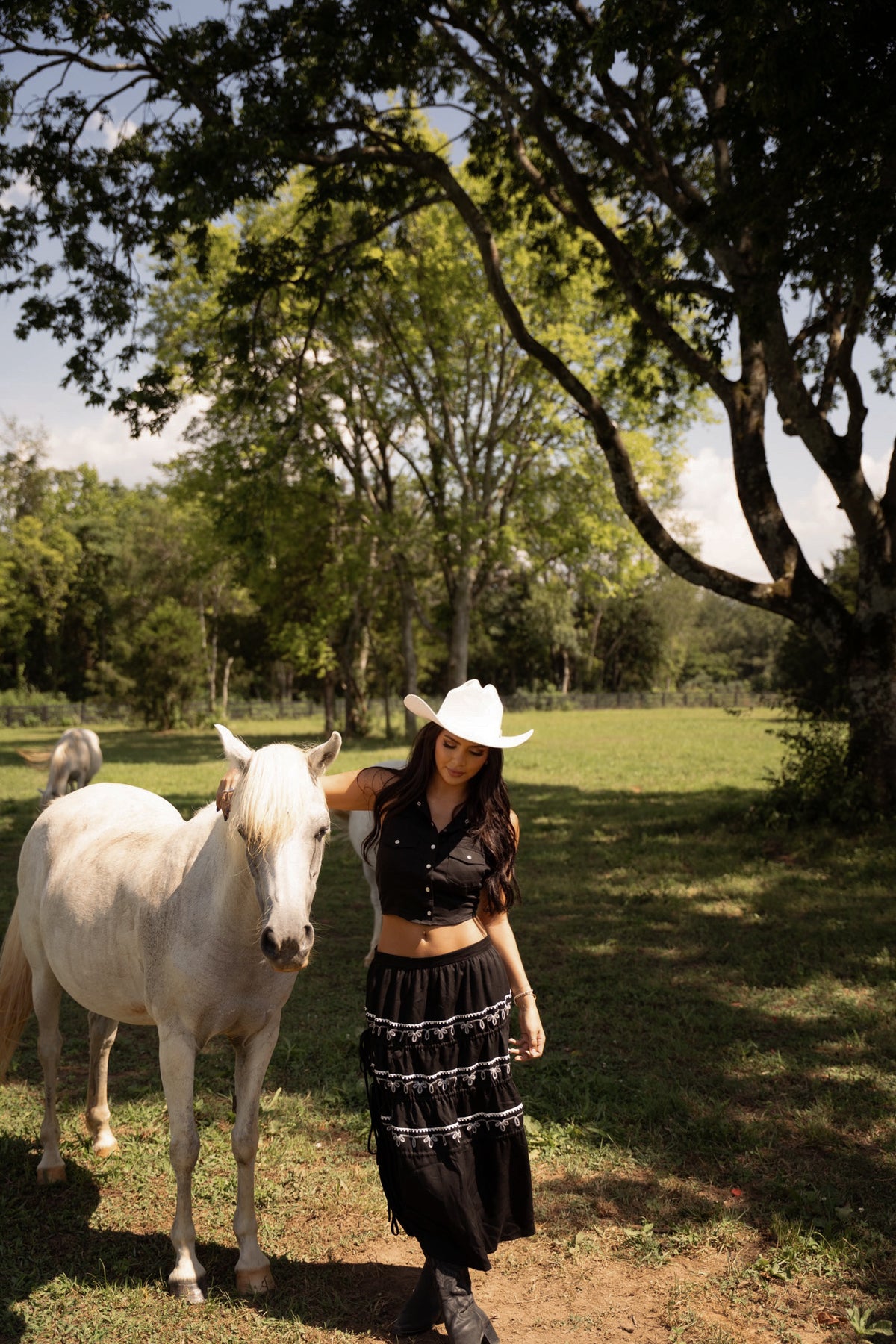 Woman walking a white horse wearing the H Bar C Coachella black tiered western skirt.