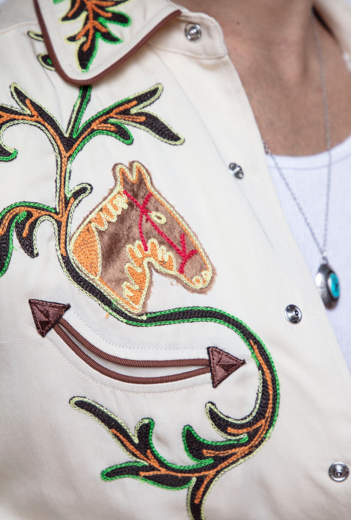 Close-up of the embroidered horse head and arrows on the front of the H Bar C Calabasas off-white western shirt.