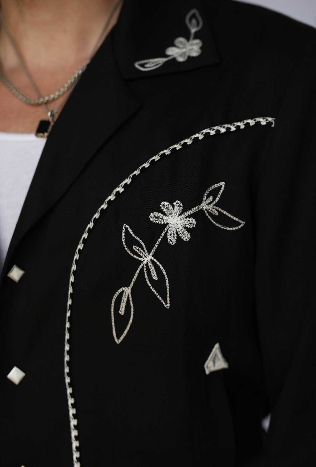 Front panel close-up of the white floral chain stitch on the H Bar C Bolero Nogales black jacket.