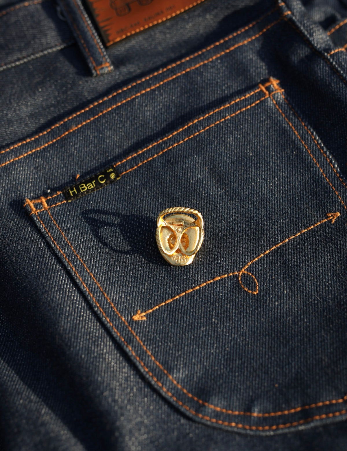 H Bar C cowboy hat scarf slide with rhinestones displayed on raw denim jeans.
