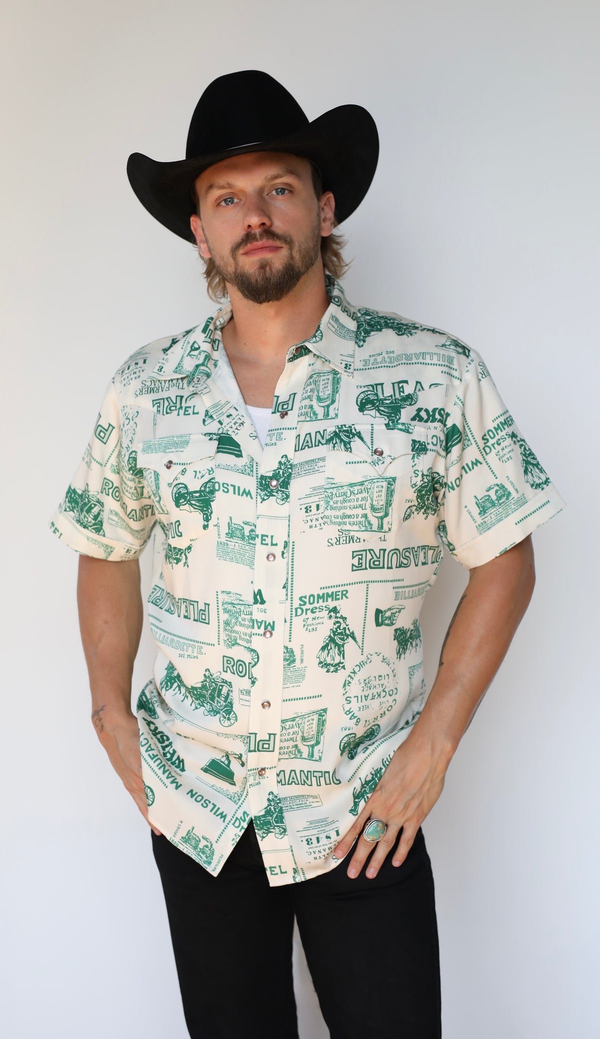 Front view of the H Bar C Newport Somerville green print western shirt tucked into black jeans.