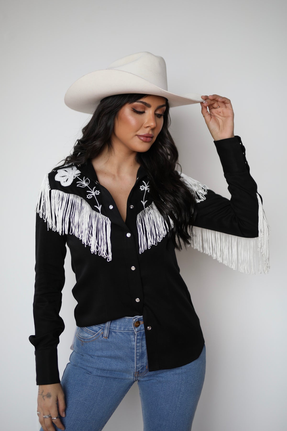 Woman tipping her hat in the H Bar C Taos black fringe western shirt for women.