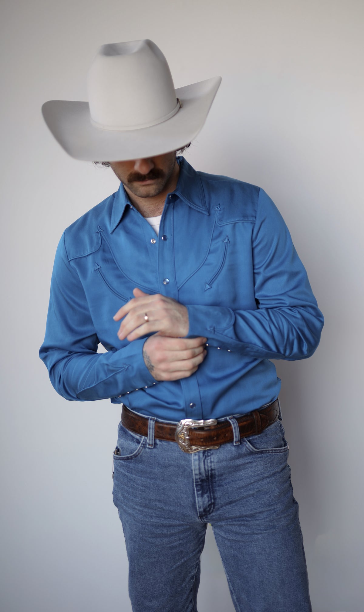 Man fastening the cuff of the H Bar C Reno royal blue Tencel western shirt.